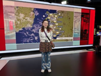 girl standing in front of the bbc news weather screen