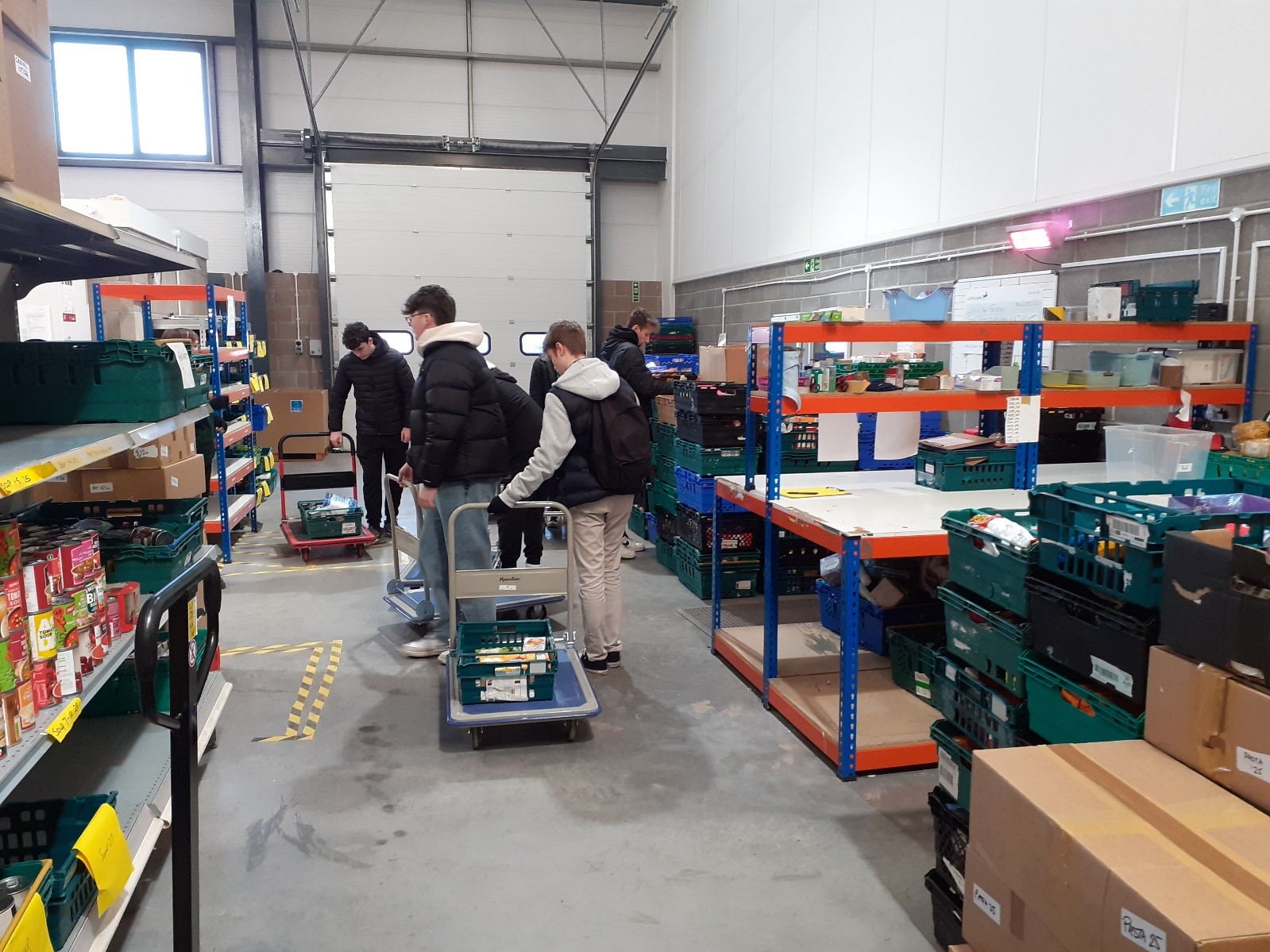 Learners moving trolleys with food around the warehouse