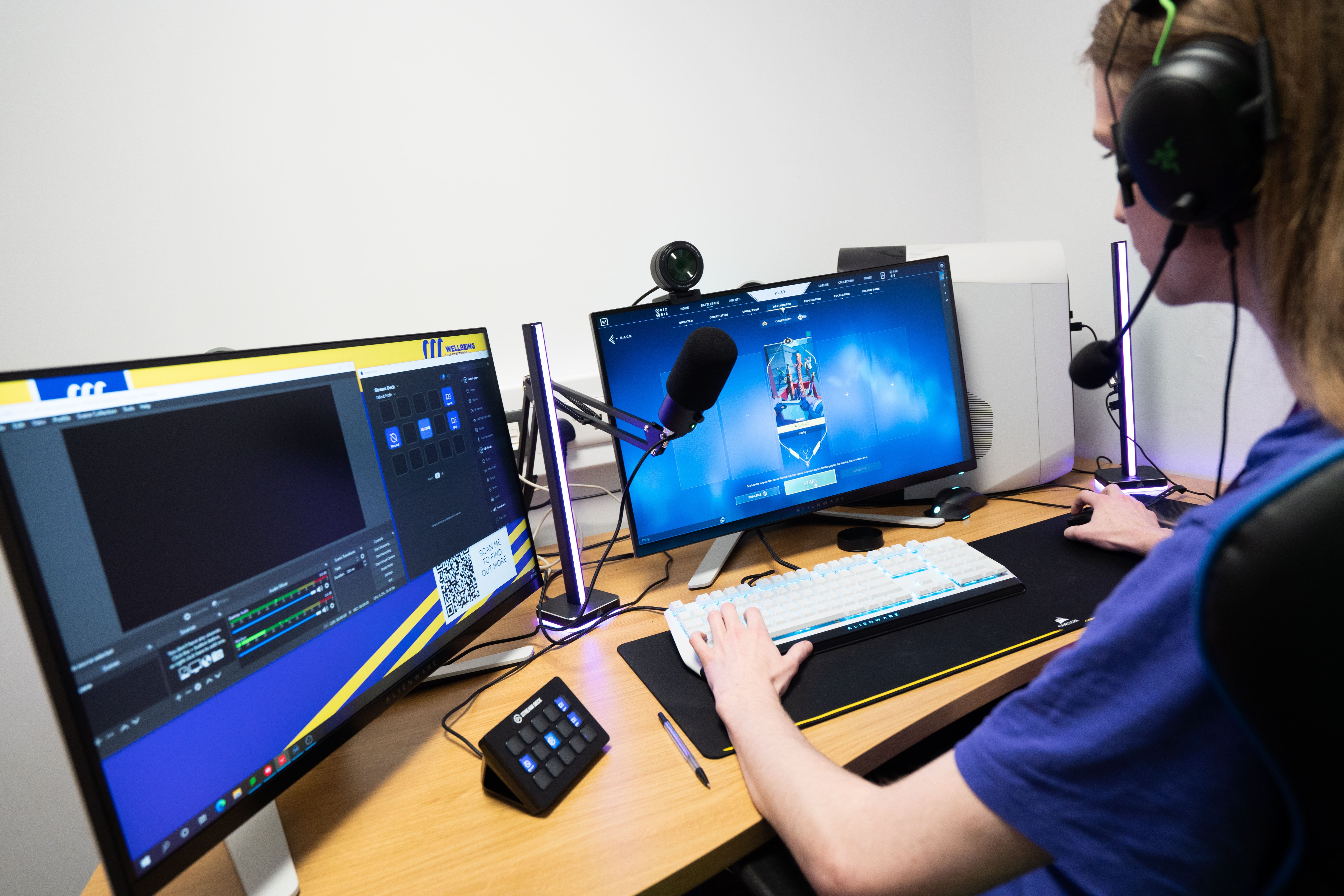 Closeup of a student practicing streaming on a dual monitor setup with mic