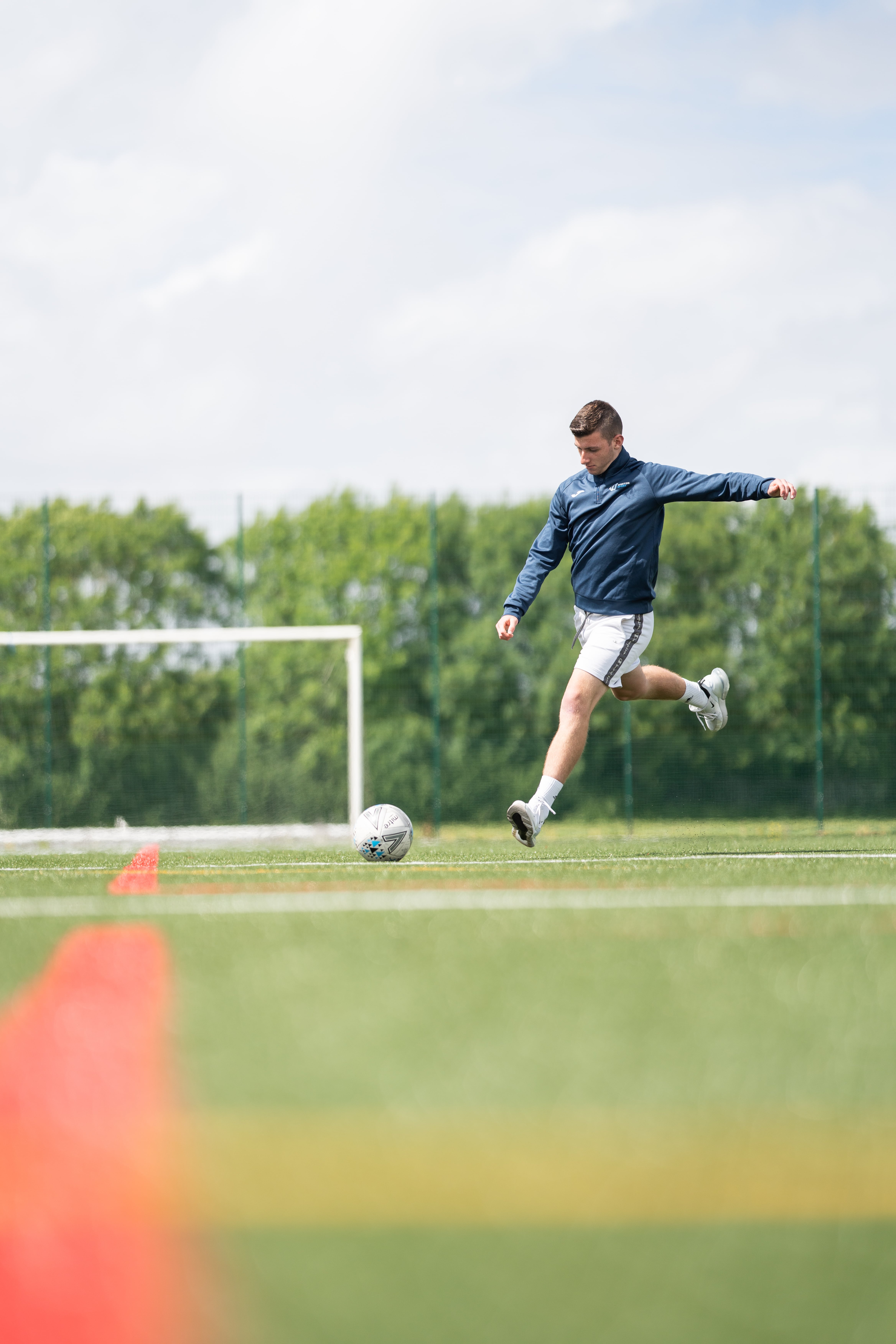 student about to kick football on astro turf