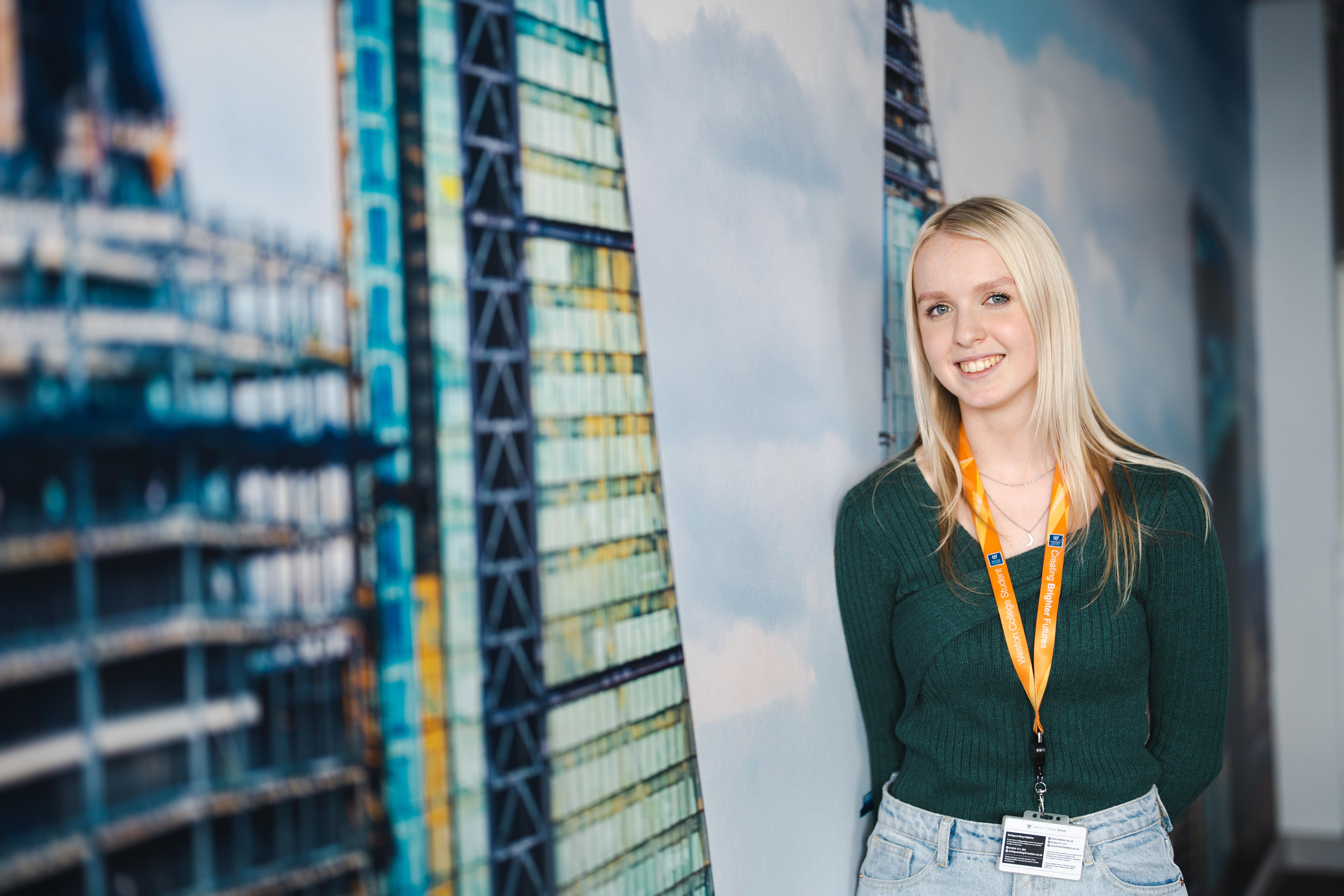 female business student stands in front of a picture of canary warf