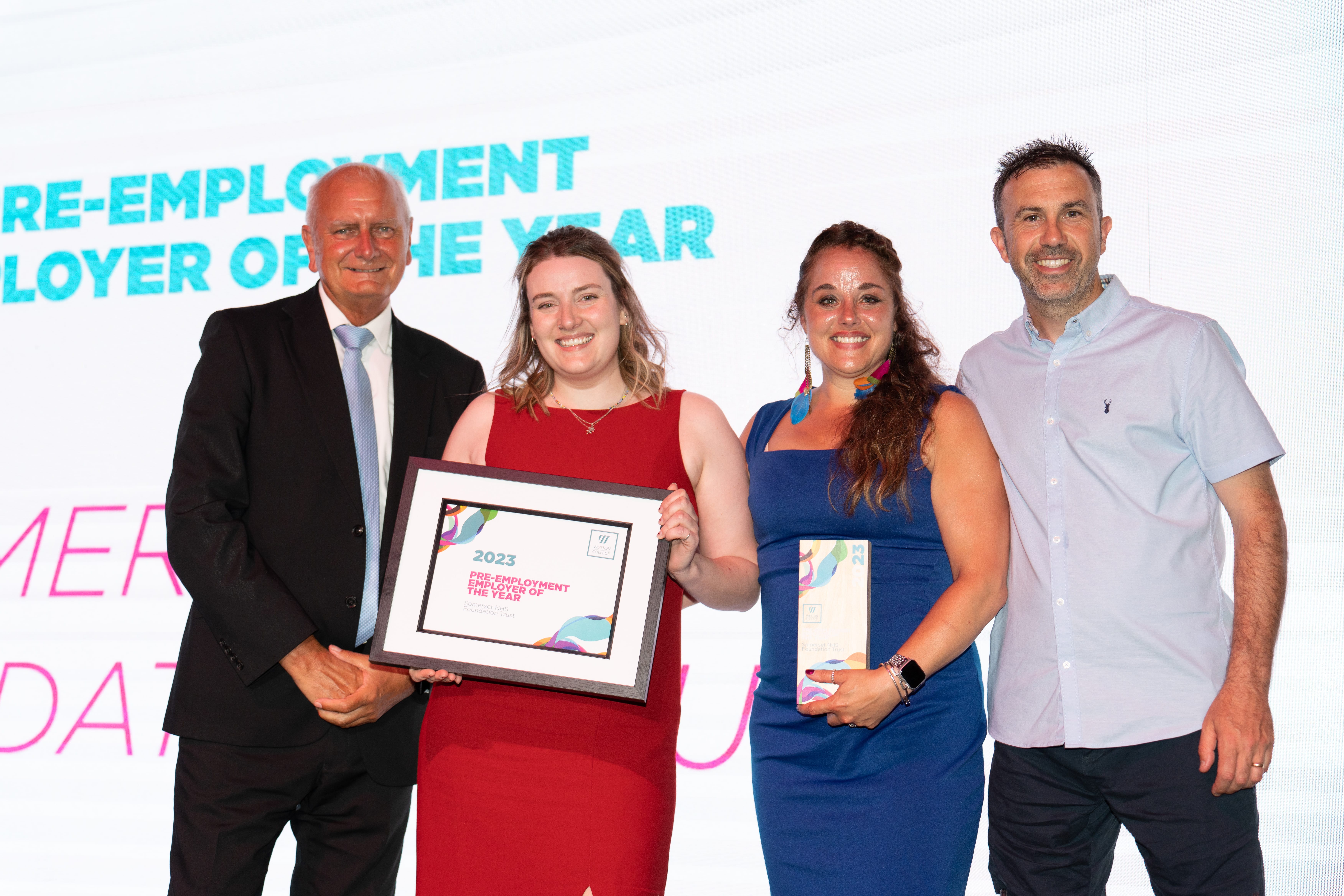 Somerset NHS Trust, on stage holding thier award next to Andy Lewis