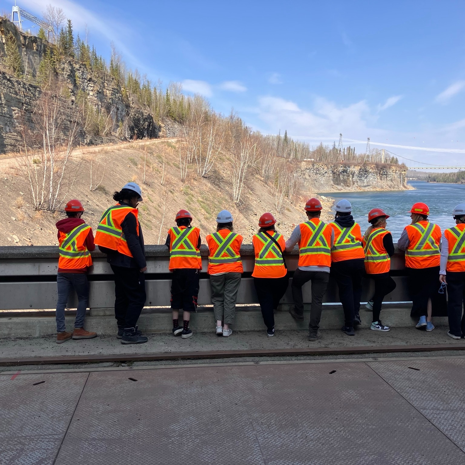 Students wearing Hi-Vis jackets looking out over a river