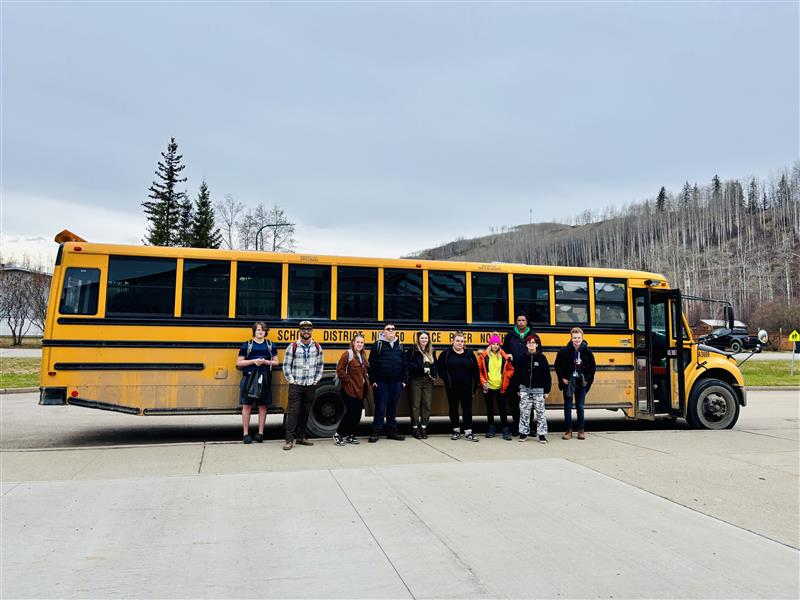 Students standing in front of a yellow school bus