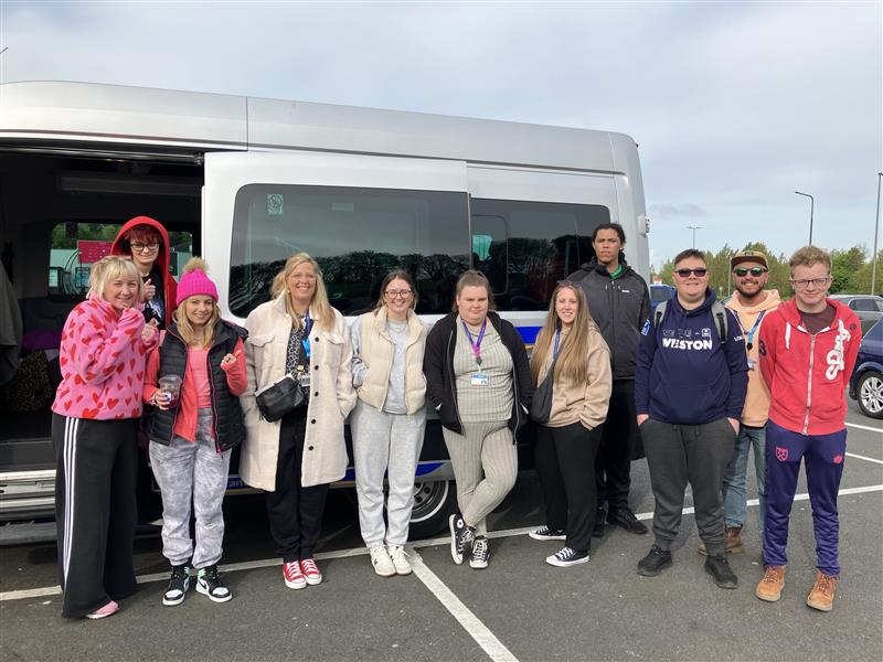Students and staff standing in front of a mini bus