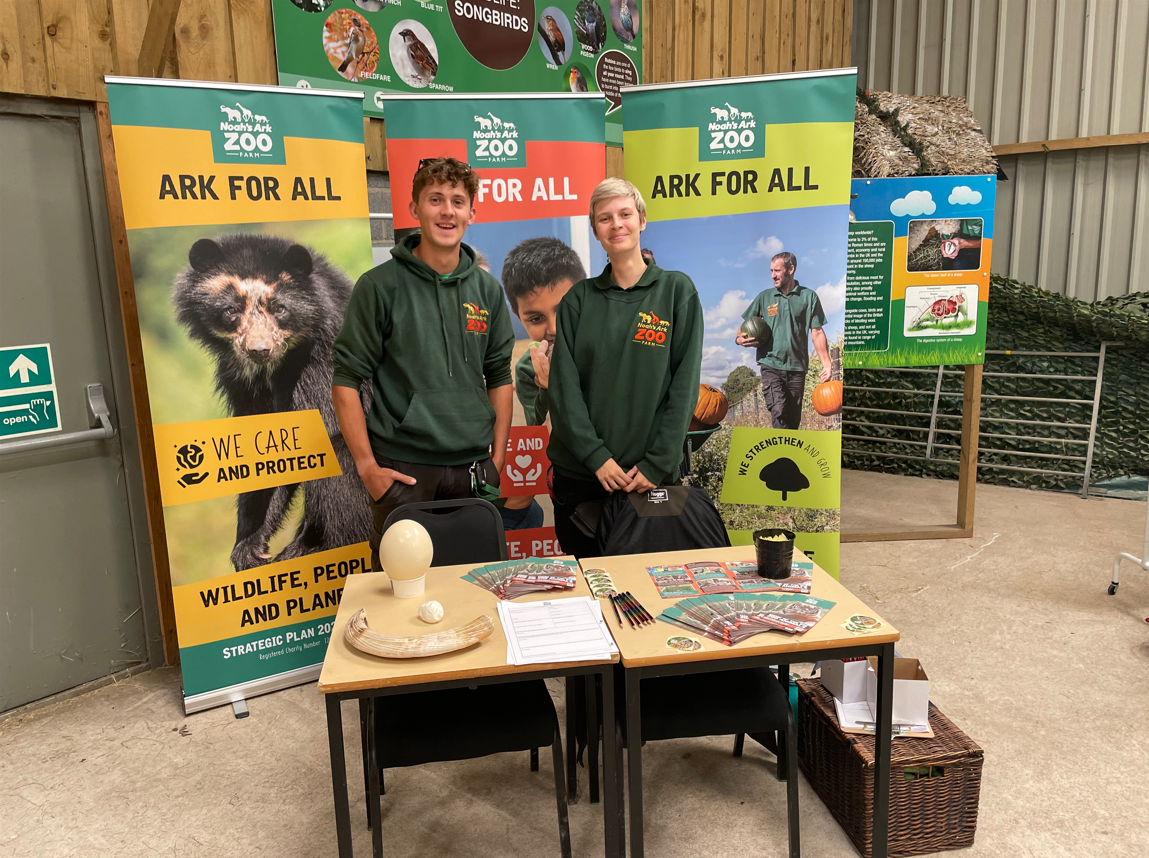 Former student, Andrew, and colleague standing by Noah's Ark Zoo banners