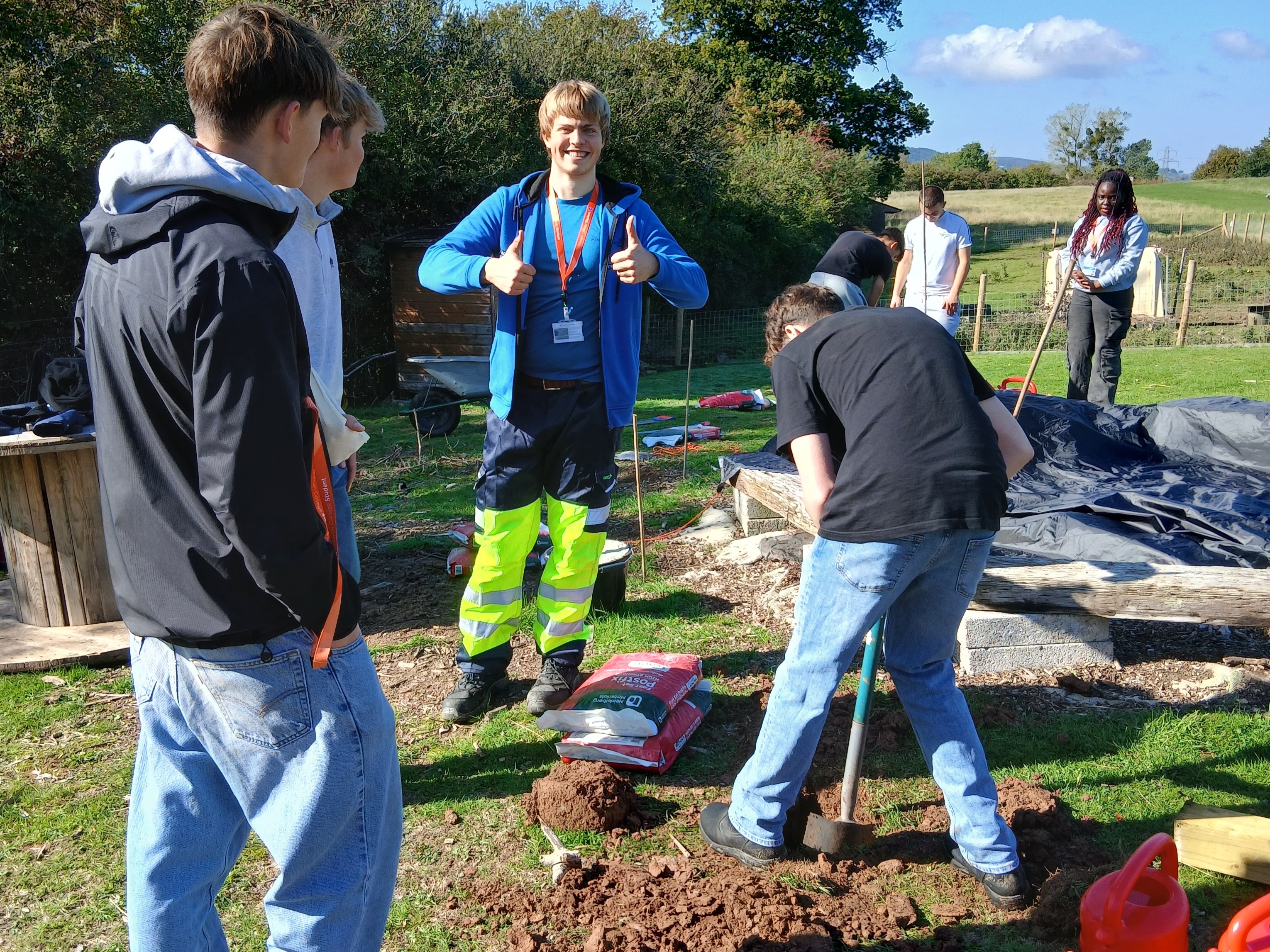 Students digging holes and one student putting their thumbs up