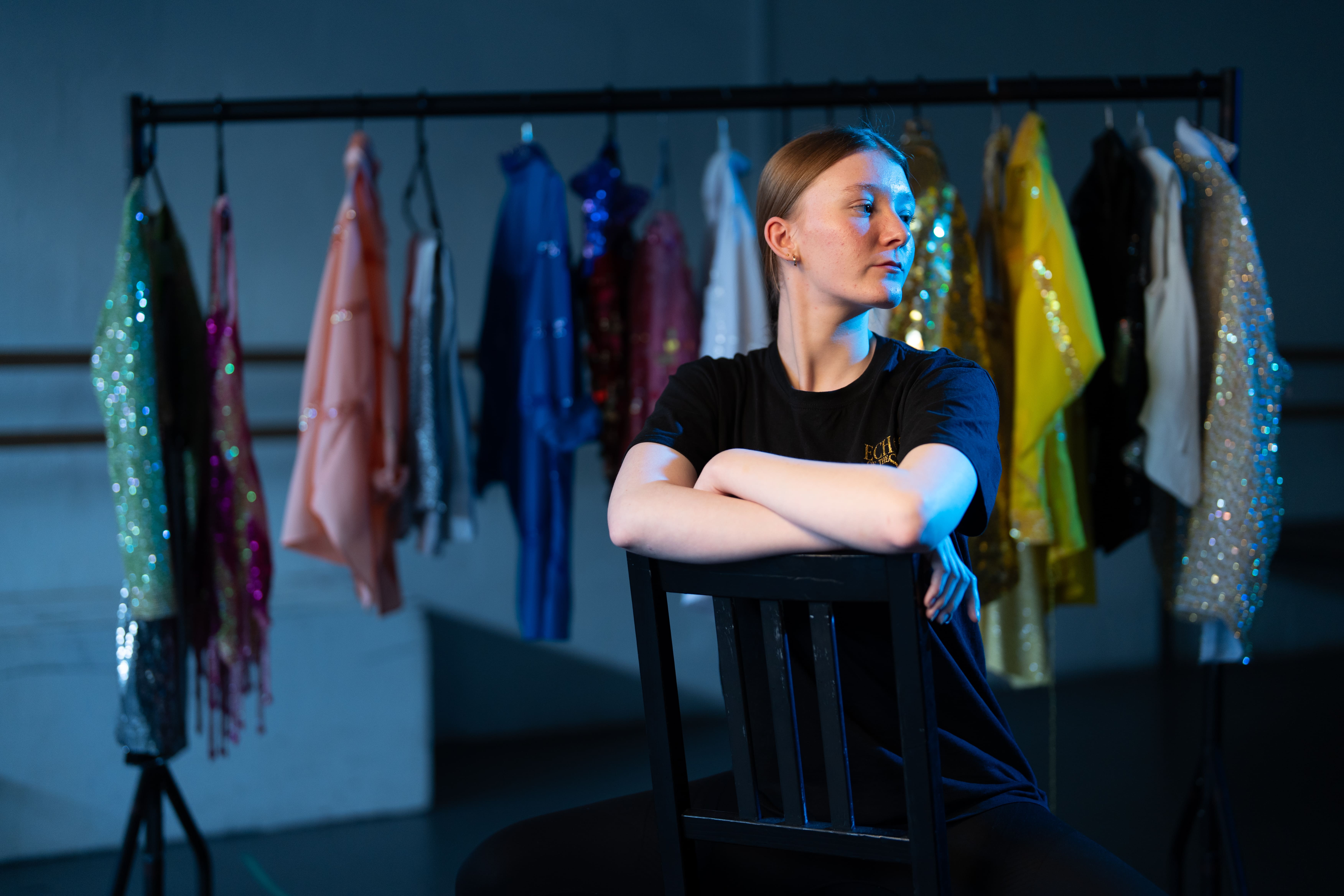 student sitting on chair infront of costume rack