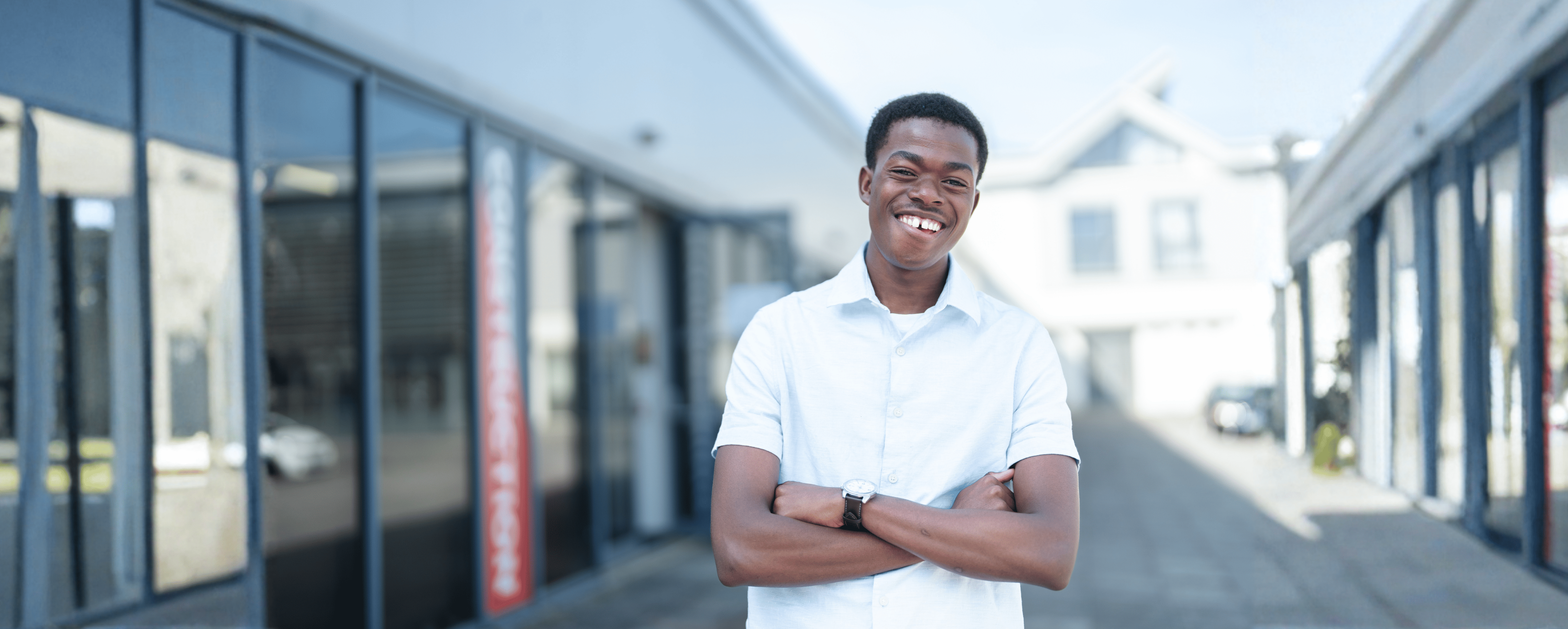 male student standing smiling with his arms crossed 