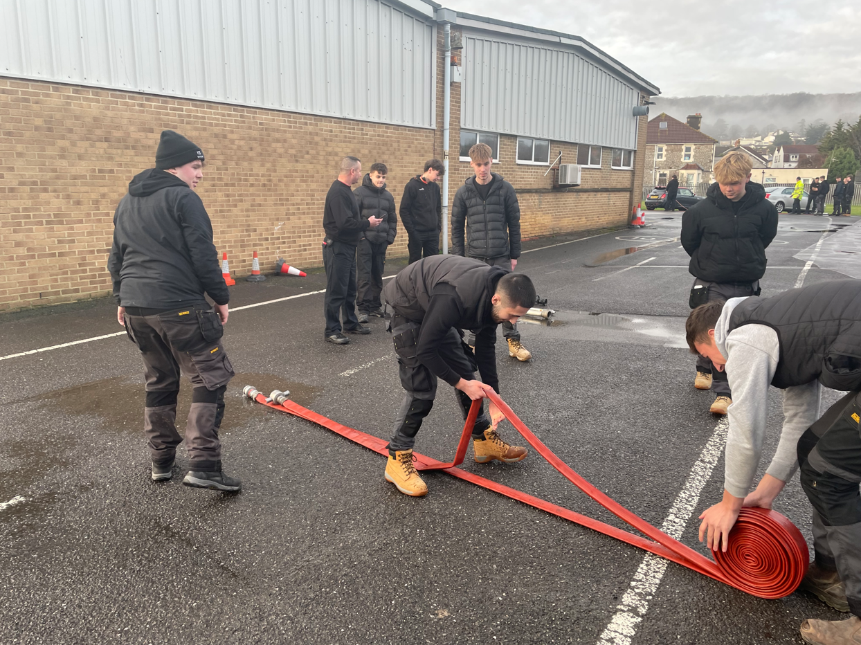 students rolling up a hose
