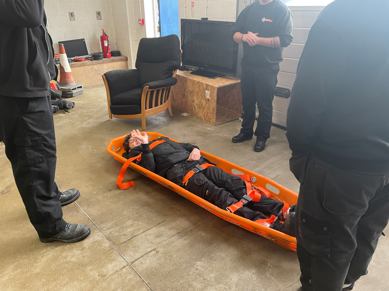 student strapped in a stretcher with his thumb up