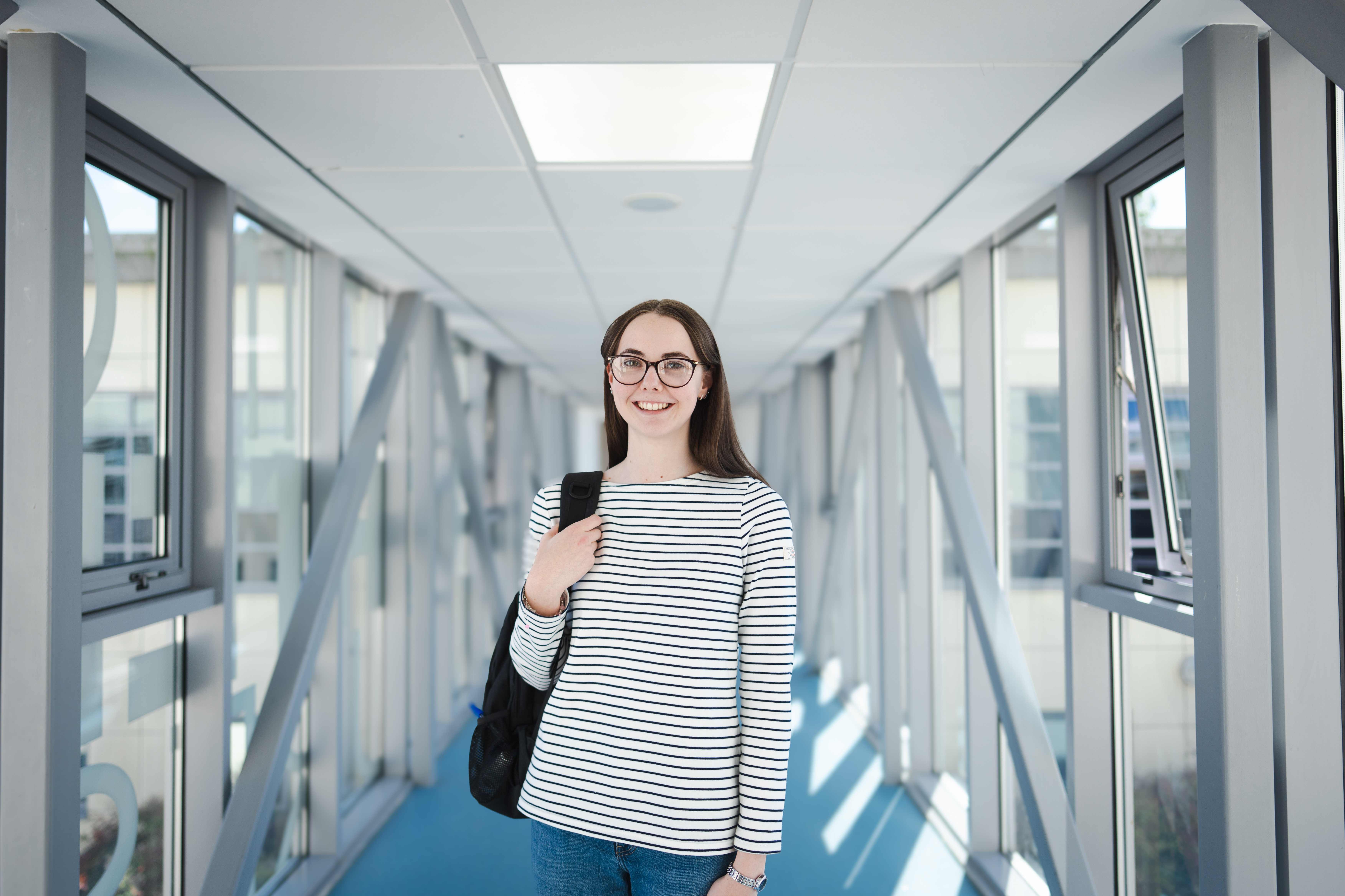 Student standing on Loxton bridge holding her bag