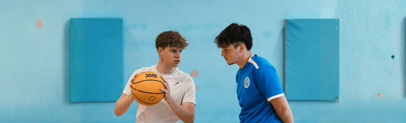 one boy holding a basket ball and the other looking at it