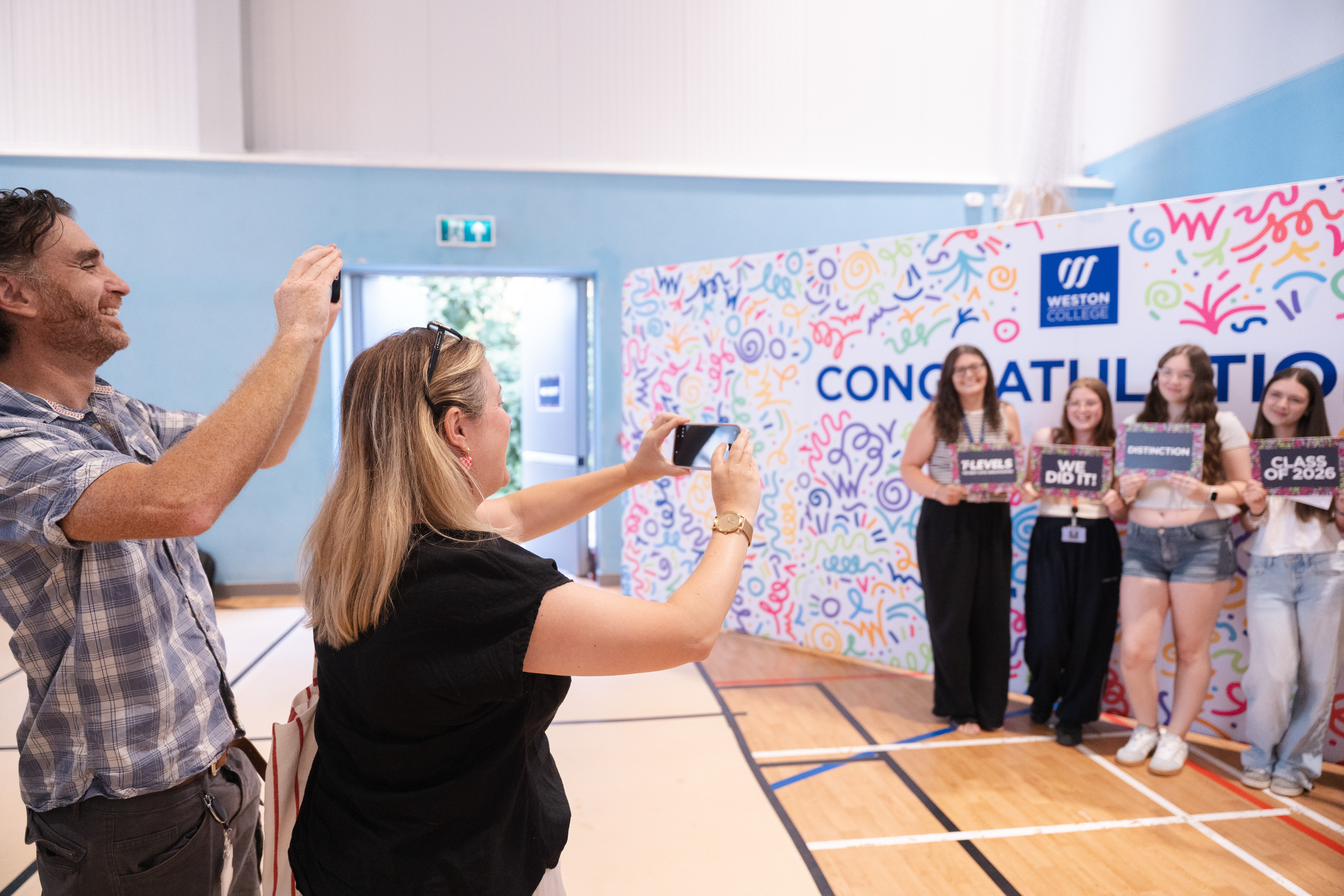 Parents taking a photo of learners in front of backdrop