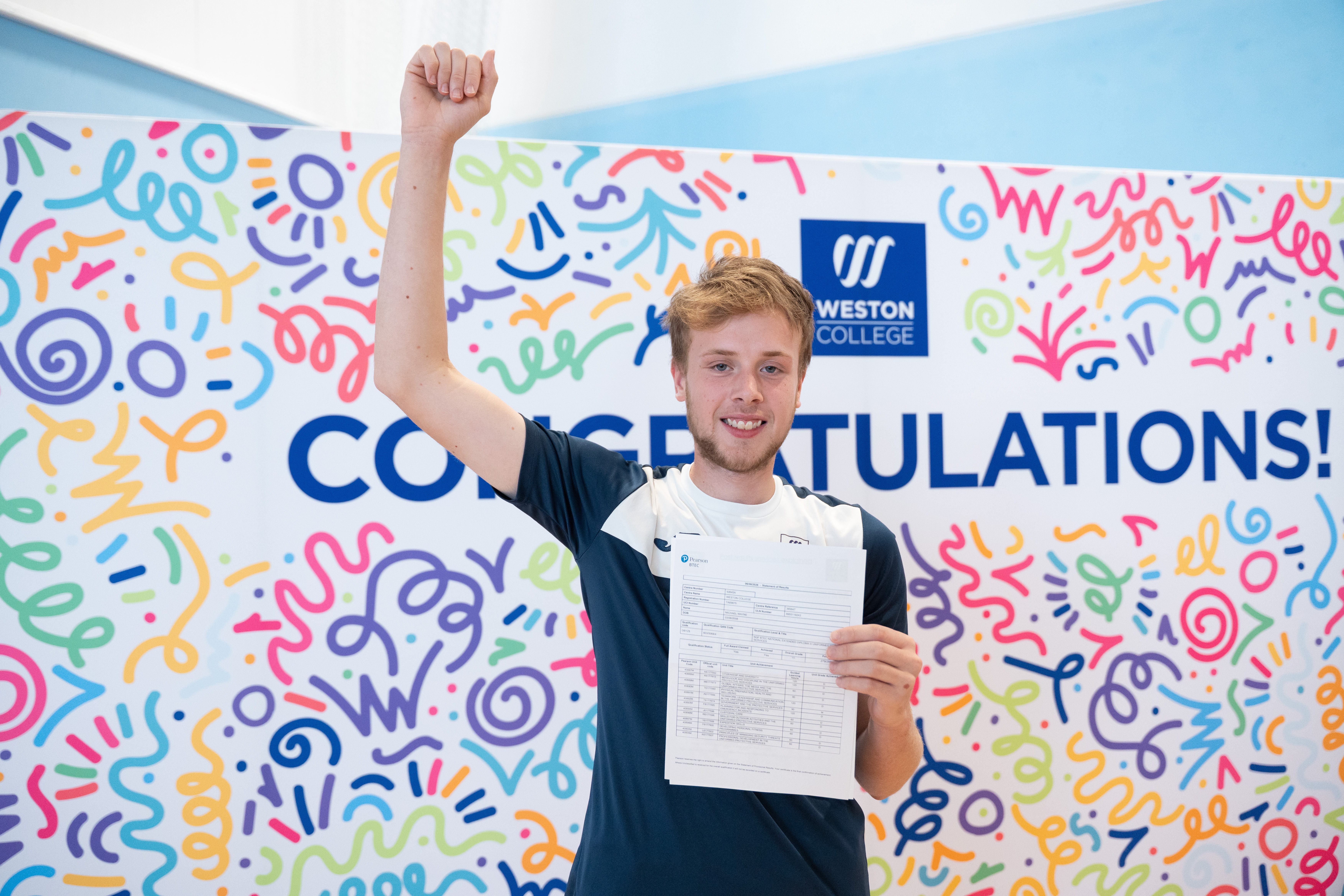 Michael cheering in front of backdrop with his results
