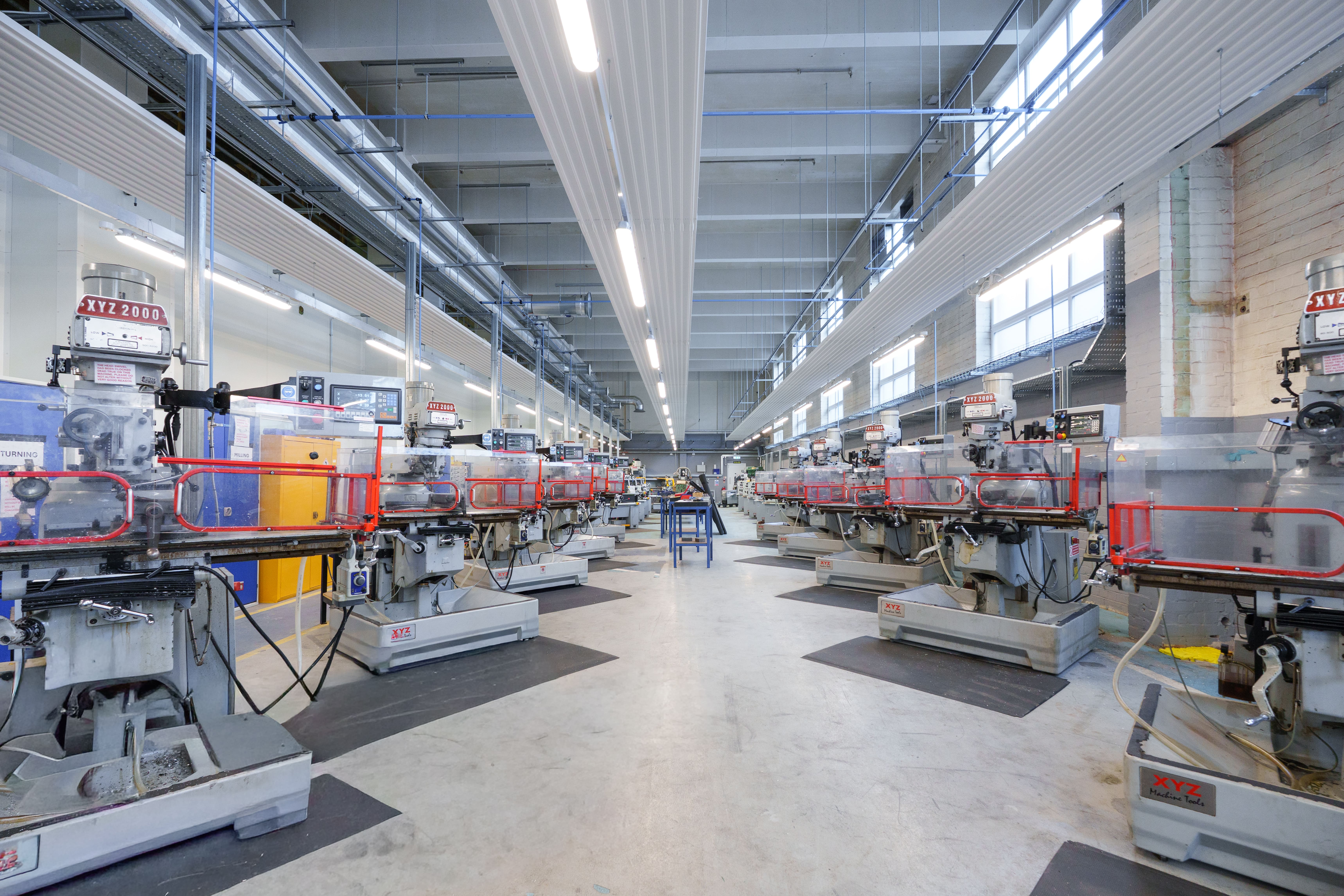 Engineering workshop with rows of milling machines and industrial equipment.