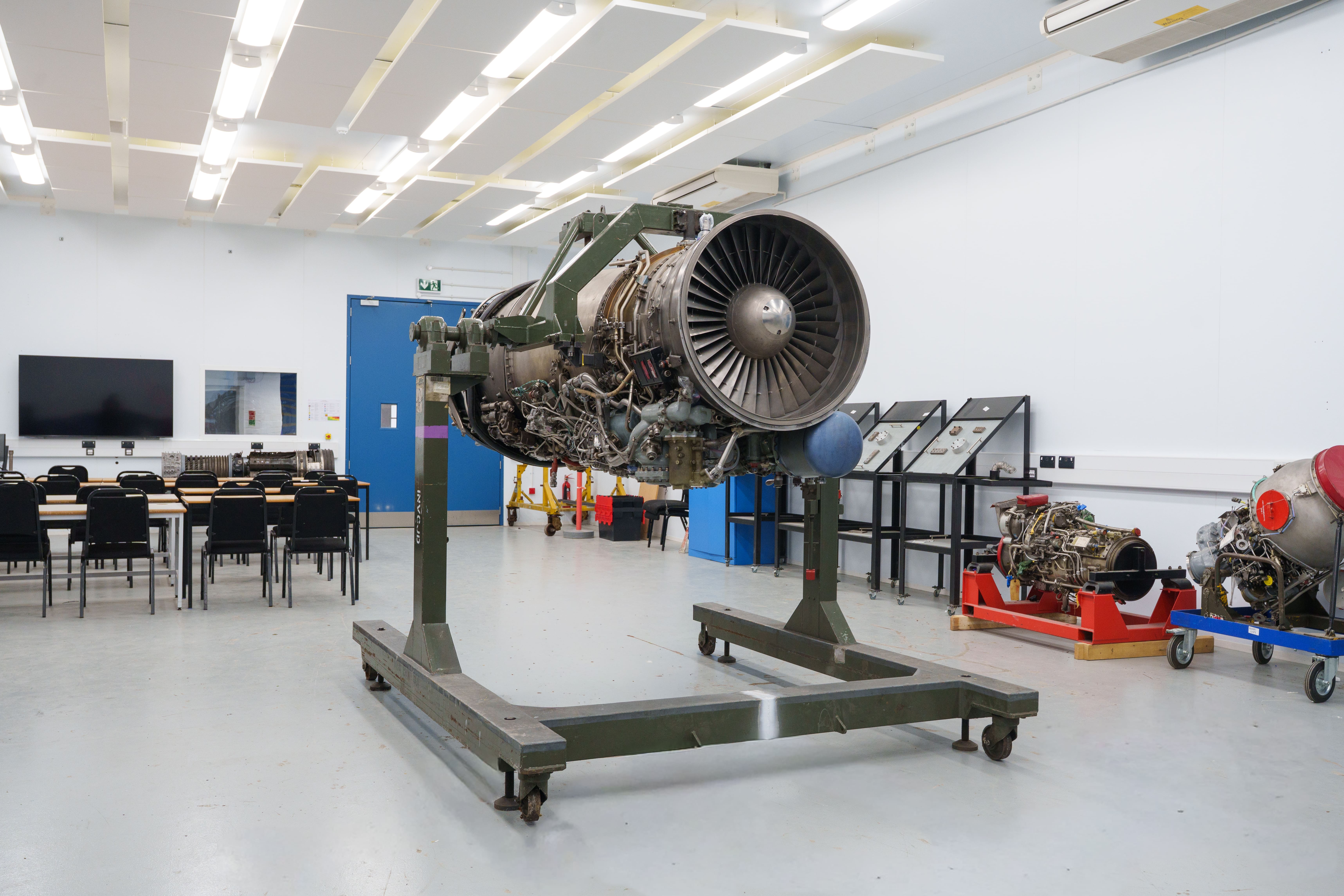 Aircraft engine displayed on a maintenance stand in an engineering training facility.