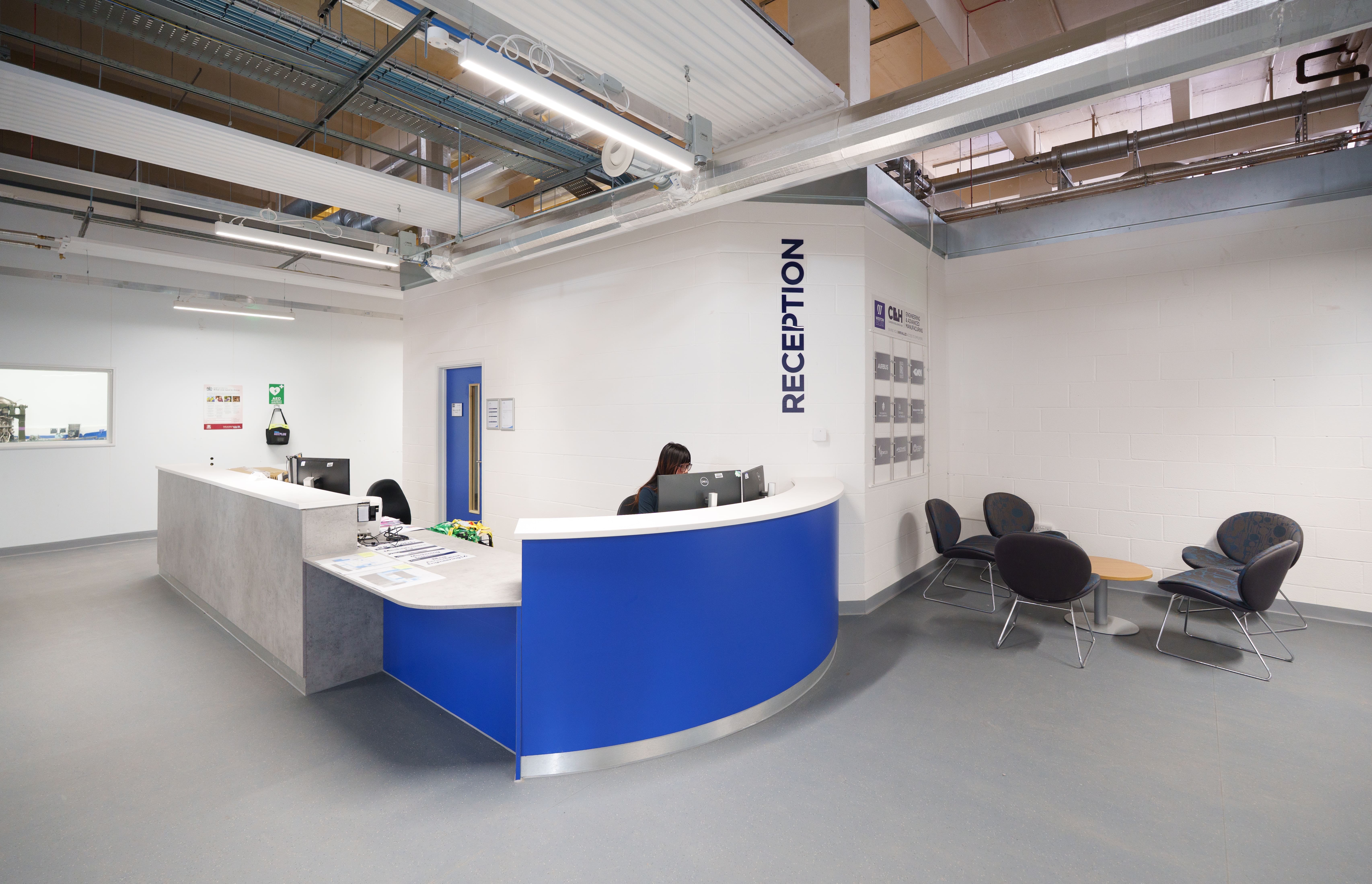 Reception area at an engineering training facility with a blue curved reception desk.
