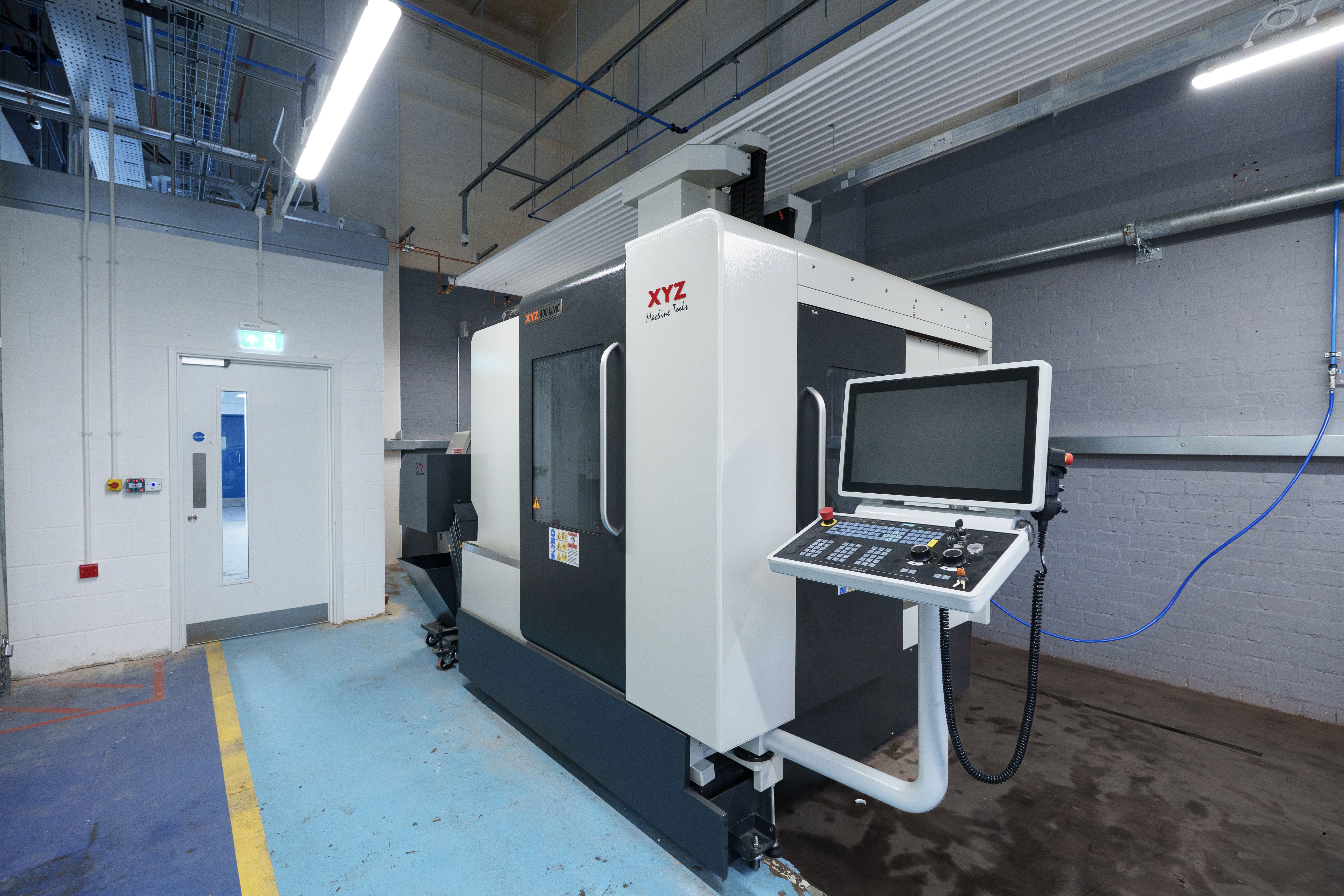 Modern CNC machining centre with a computer control panel in an engineering workshop.