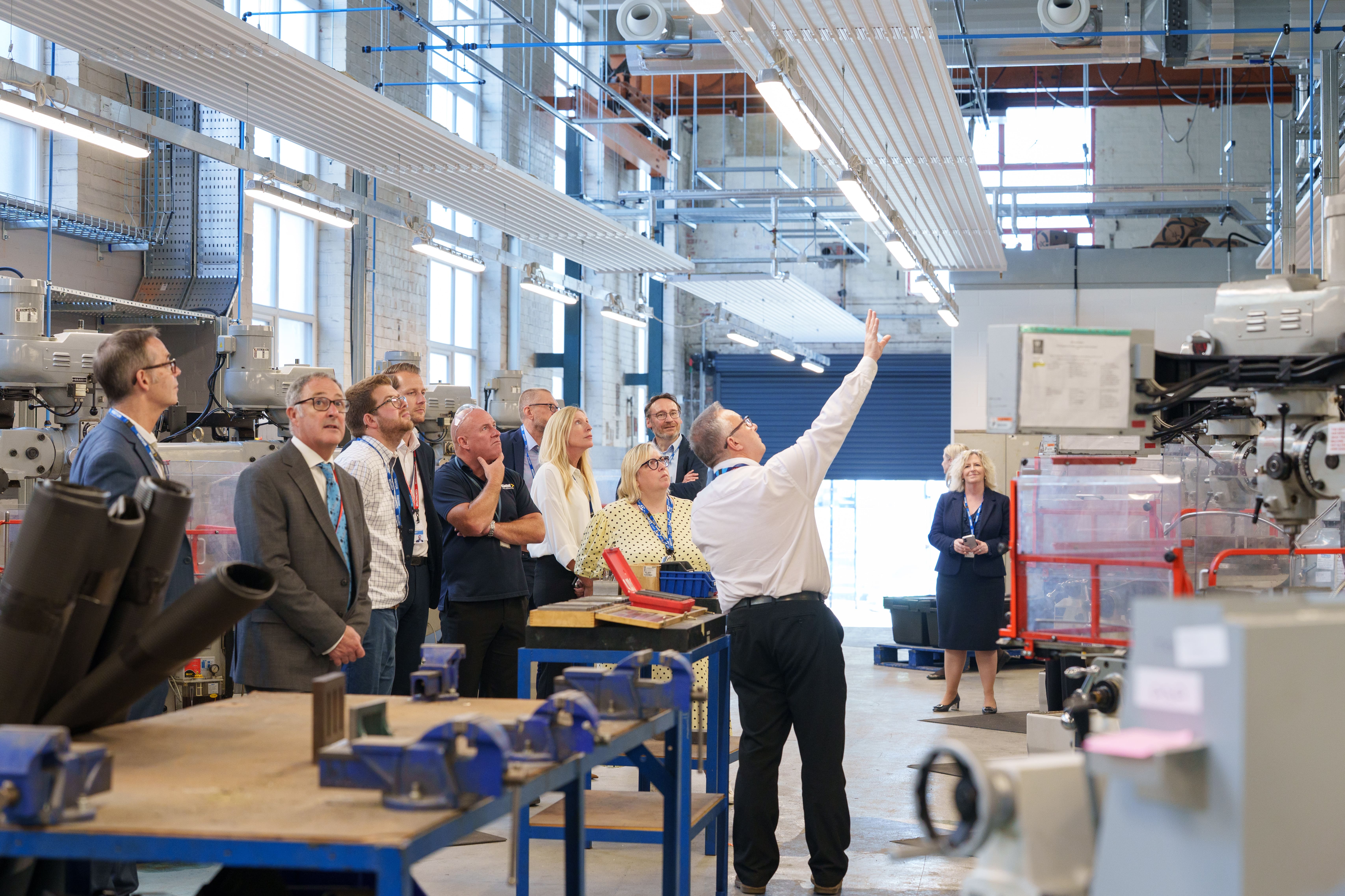 Group visiting an engineering workshop while a staff member explains the machinery.