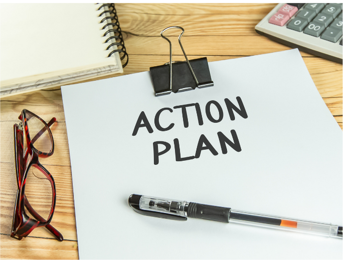 a piece of paper that says action plan, with a pen, glasses, notebook and a calculator