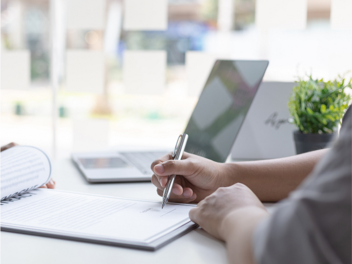 a hand holding a pen abour to write in a piece of paper