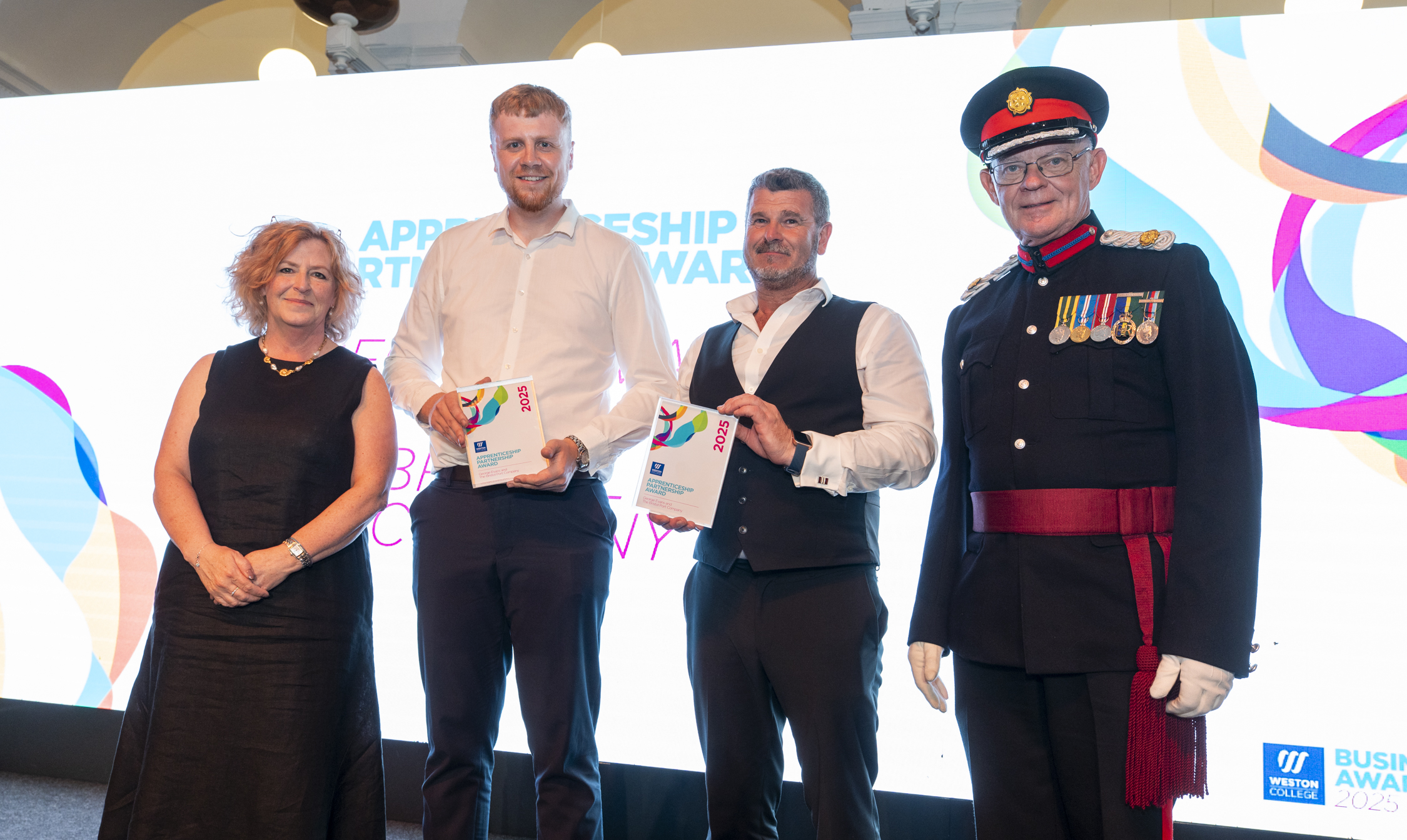 George, standing on stage with his employer, and principle Pat Jones being presented the award and posing for a picture