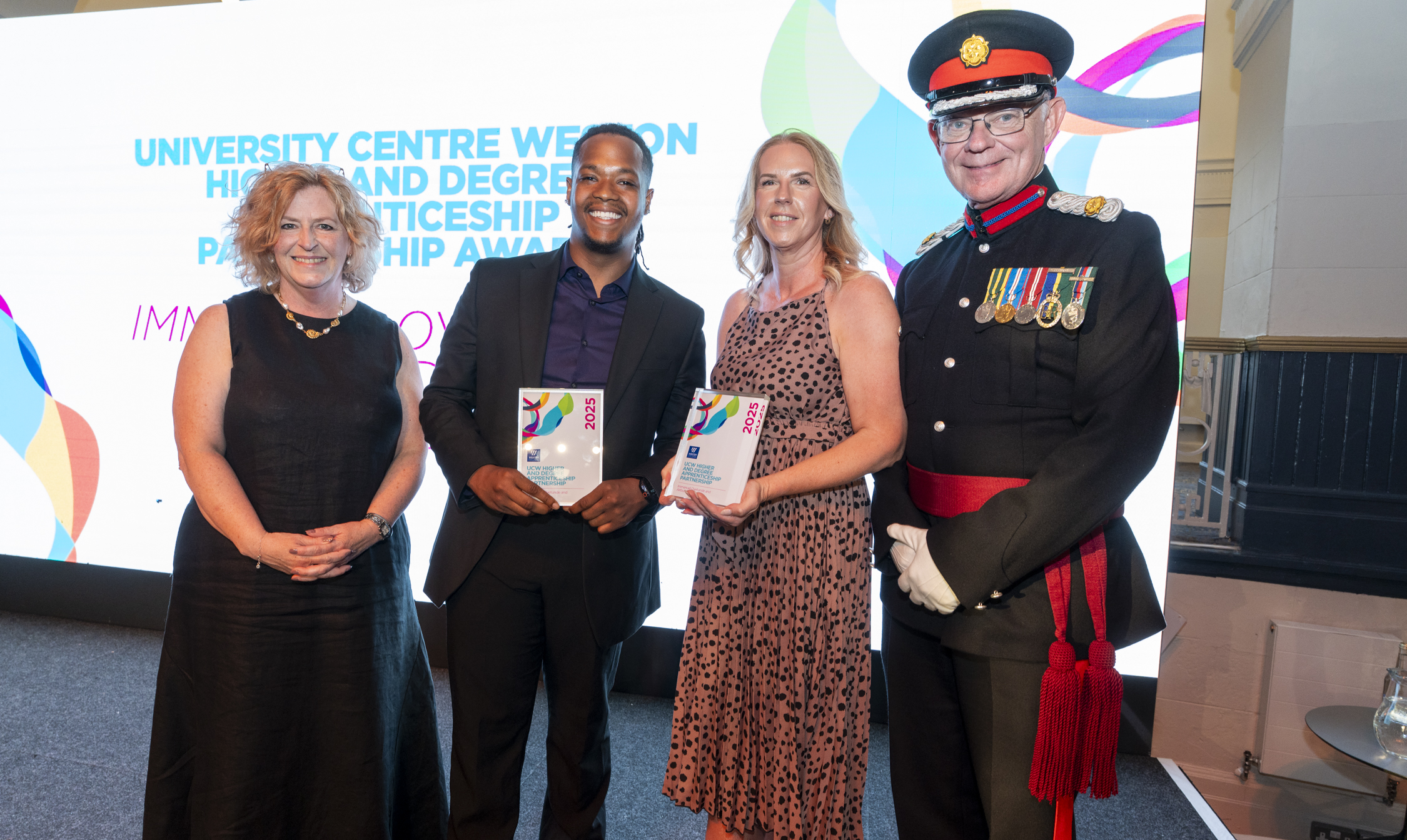 Immanuel, standing on stage with his employer, and principle Pat Jones being presented the award and posing for a picture