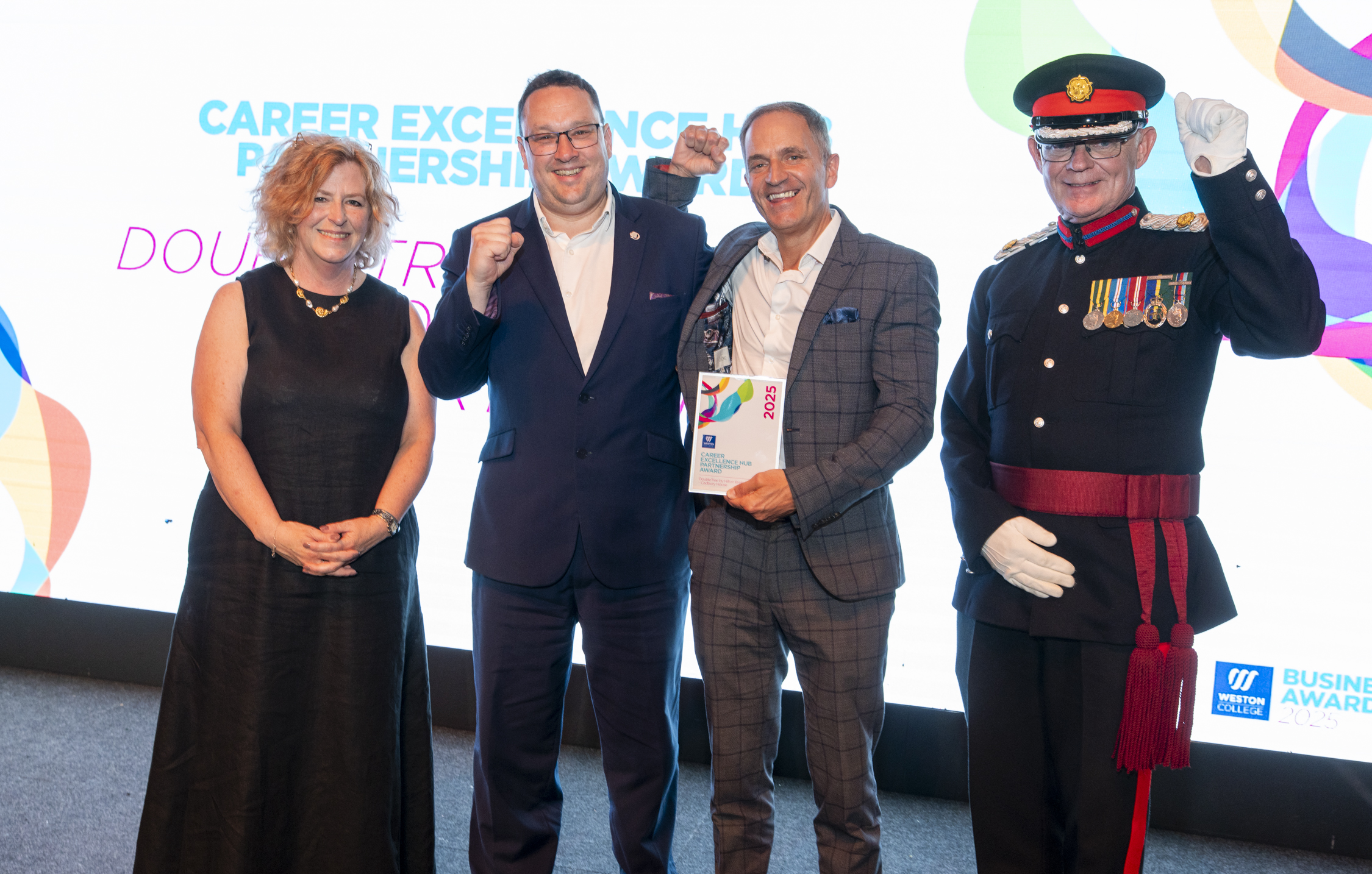 Double tree hilton staff, standing on stage with principle Pat Jones being presented the award and posing for a picture