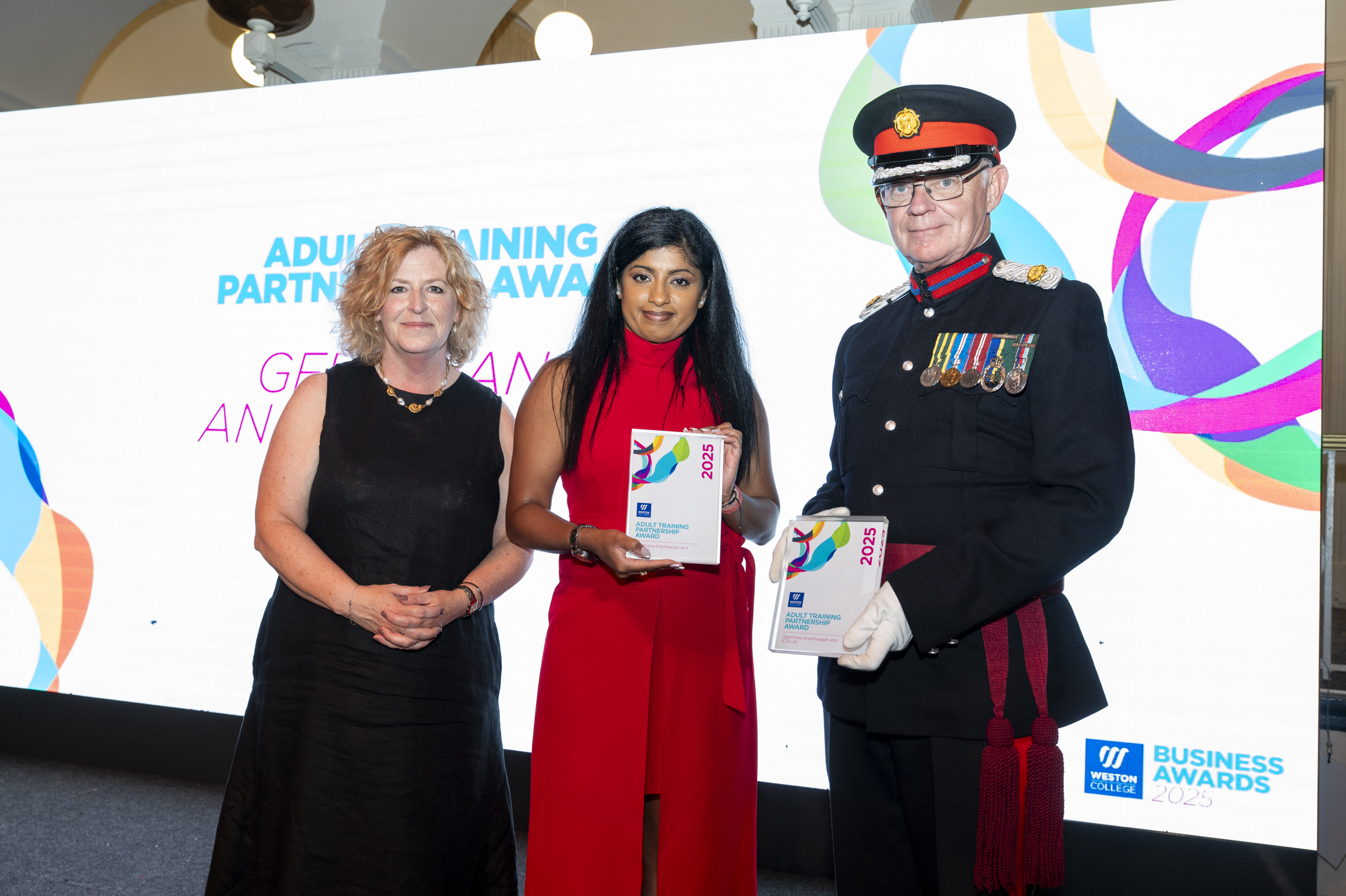 Geerthana, standing on stage with principle Pat Jones preseting the award and posing for a picture
