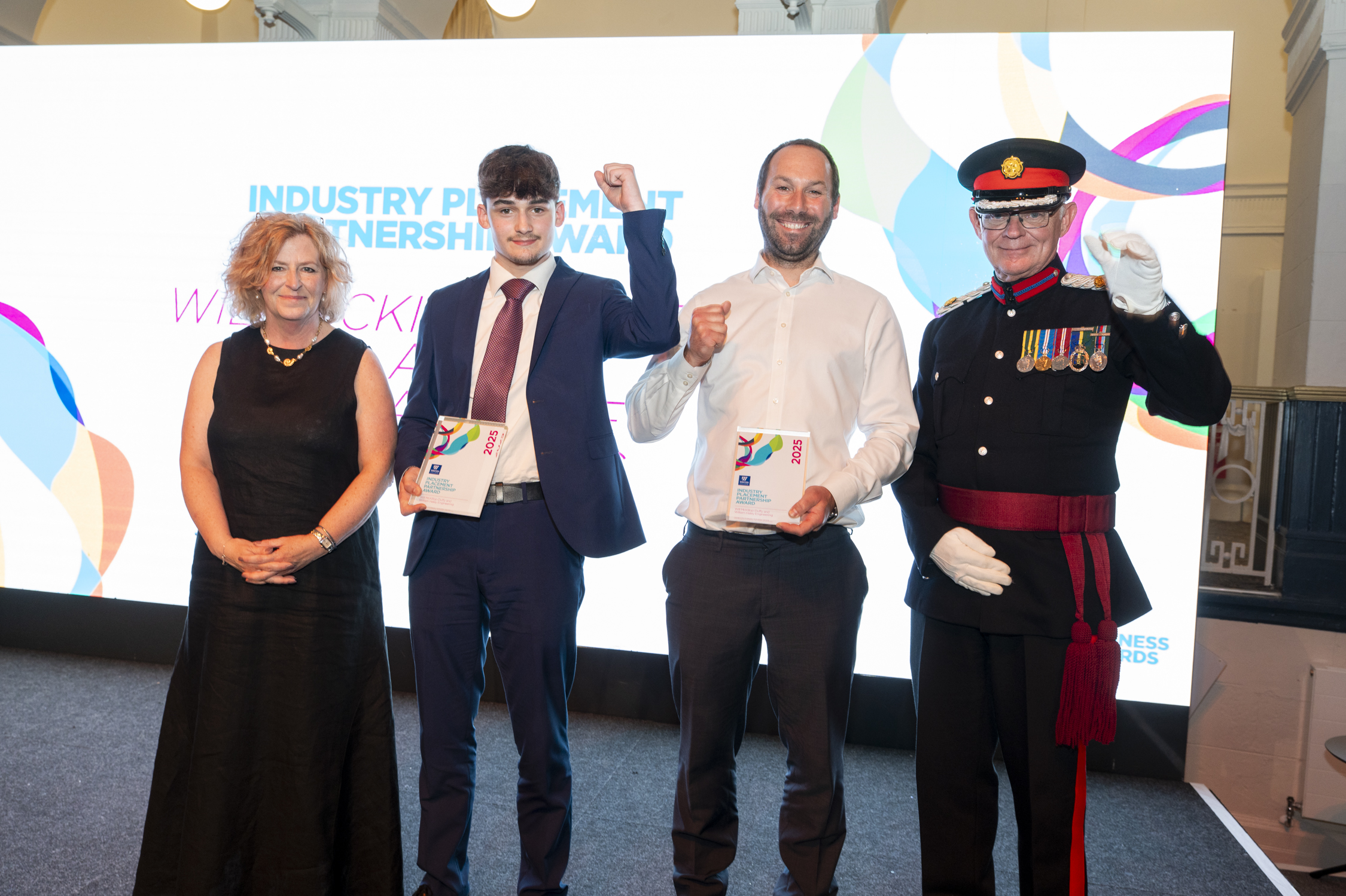 Will, standing on stage with his employer and principle Pat Jones being presented the award and posing for a picture