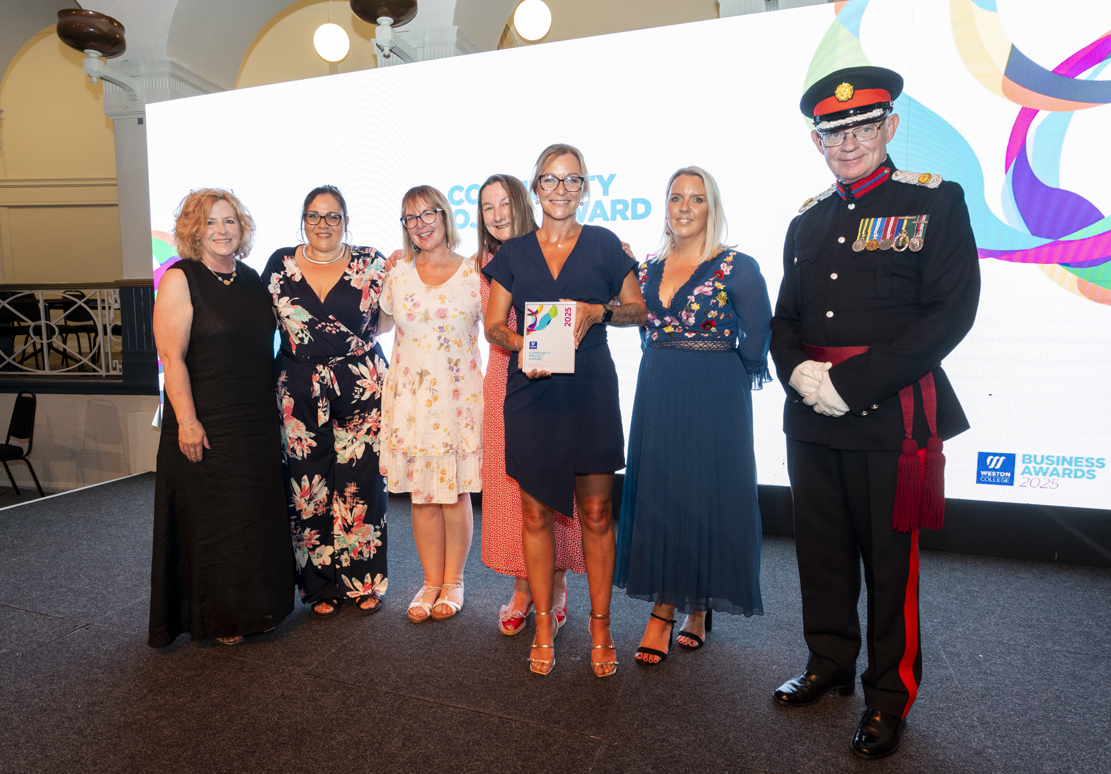 winners standing on stage with principle Pat Jones being presented the award and posing for a picture