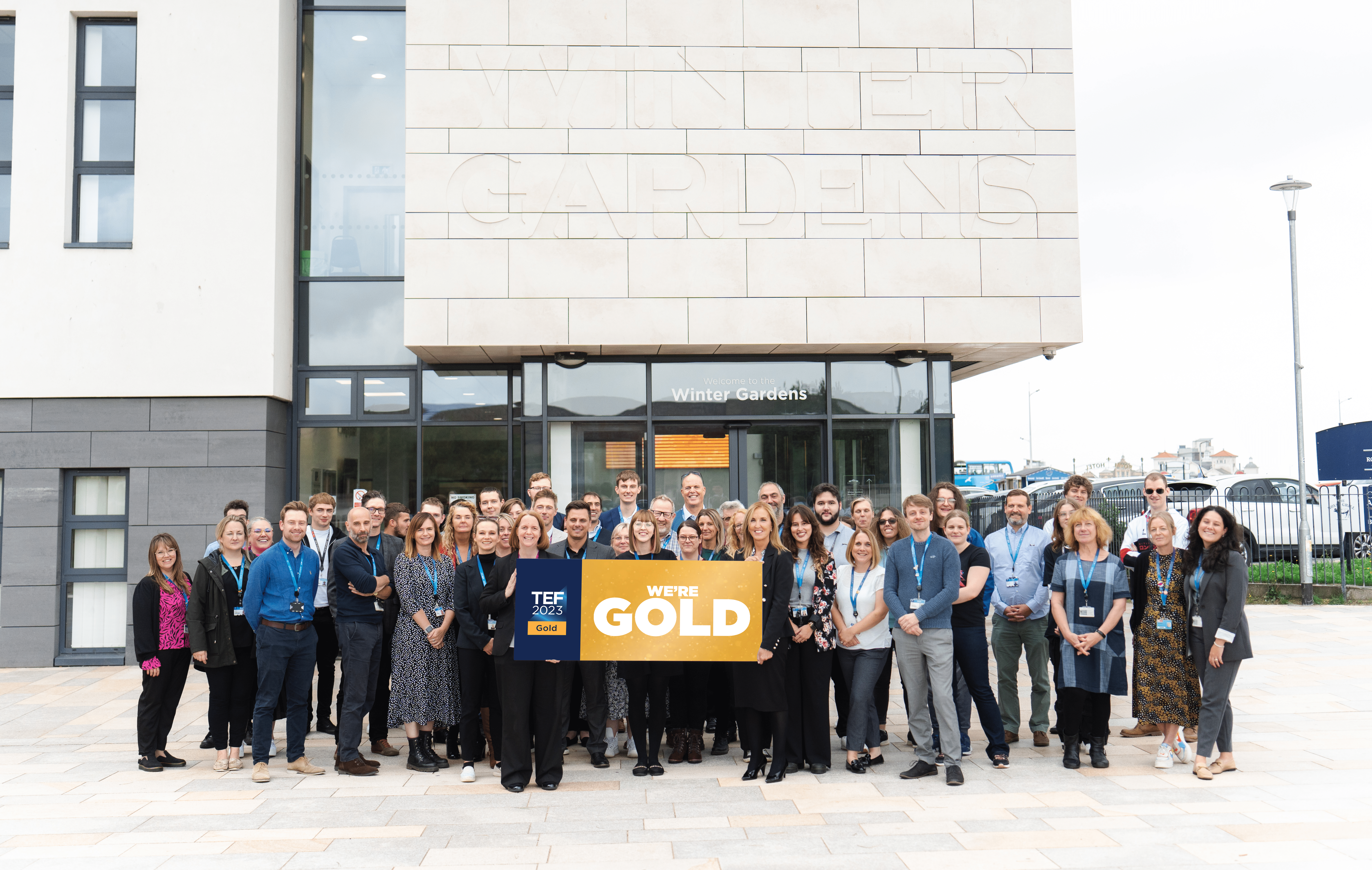 UCW Staff Posing with 'We're Gold' banner