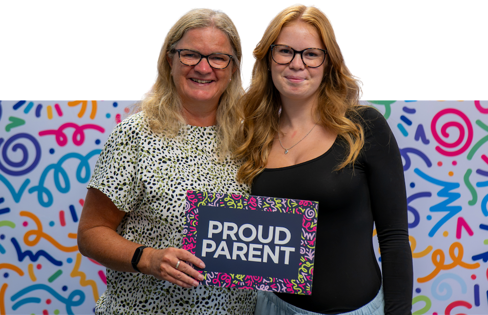 student with her mum holding sign Proud Parent