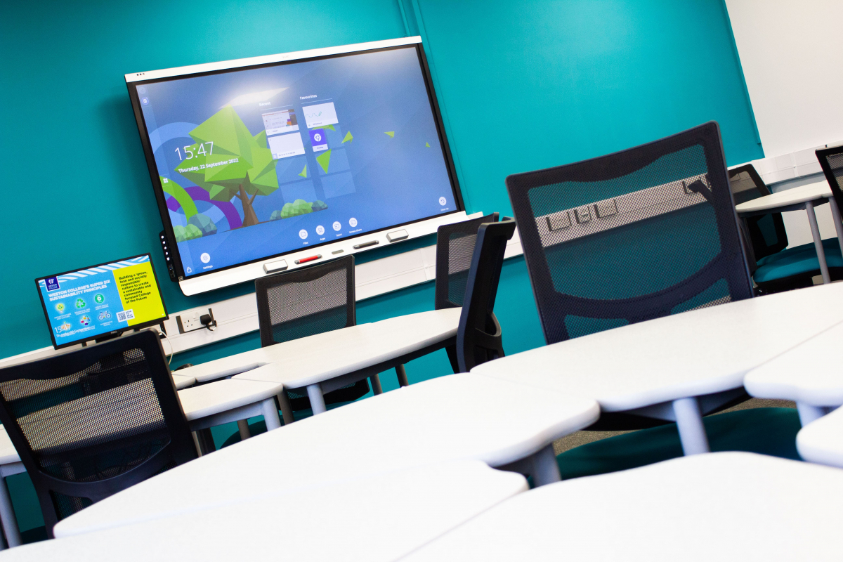 business classroom close up of circle tables with chairs around showing interactive whiteboard 