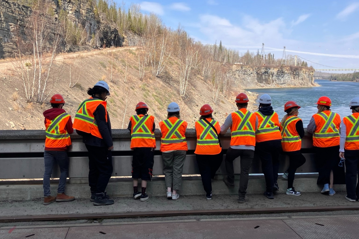 Students wearing Hi-Vis jackets looking out over a river