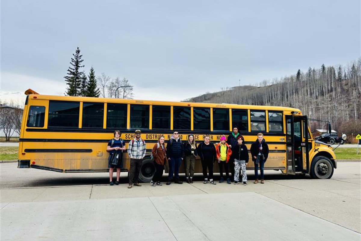 Students standing in front of a yellow school bus