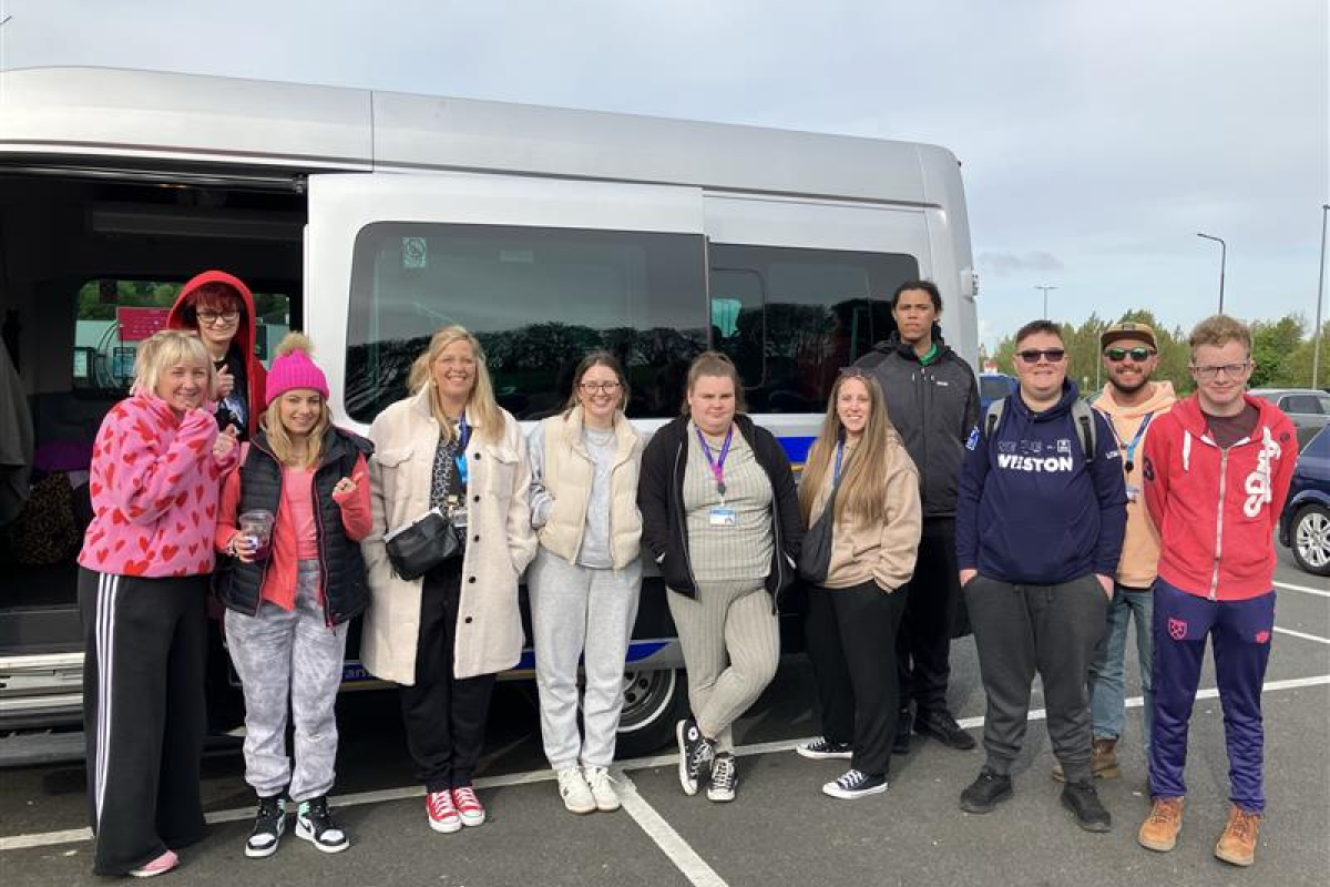 Students and staff standing in front of a mini bus