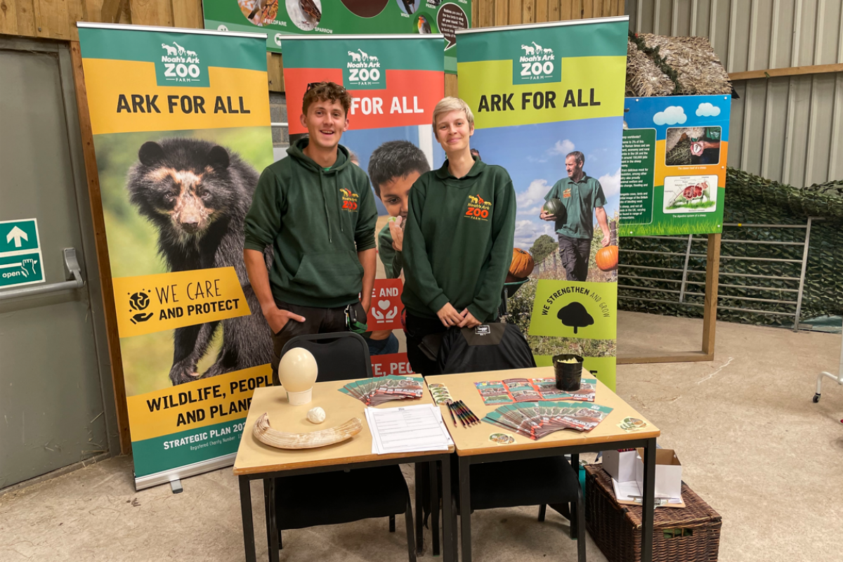 Former student, Andrew, and colleague standing by Noah's Ark Zoo banners