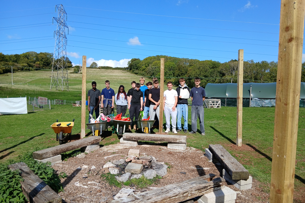 Group photo by the fire pit and wooden posts they had inserted