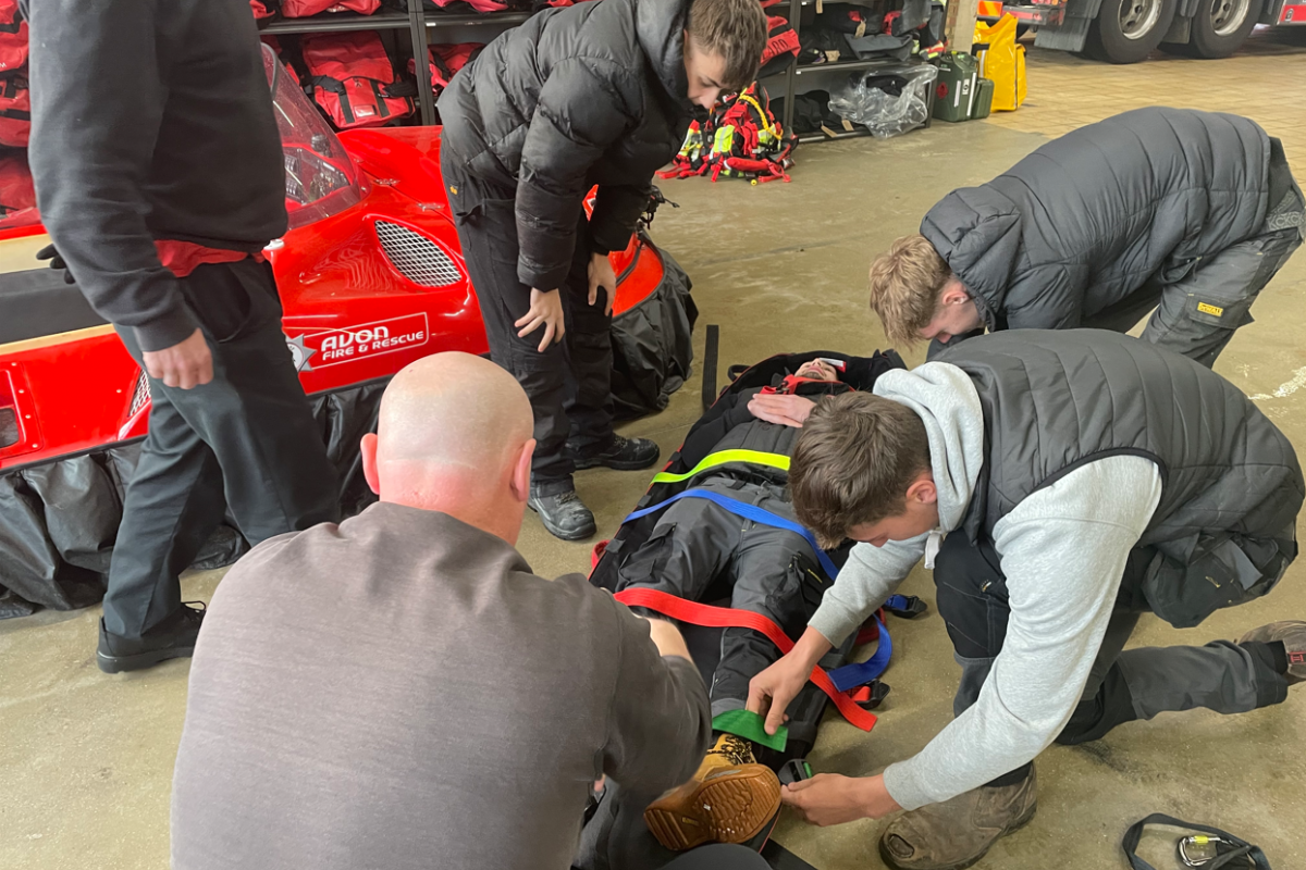 students strapping in another student onto a stretcher 