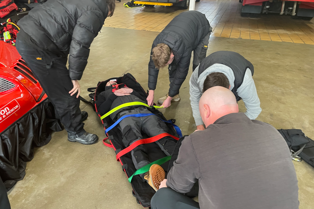 students strapping in another student onto a stretcher 