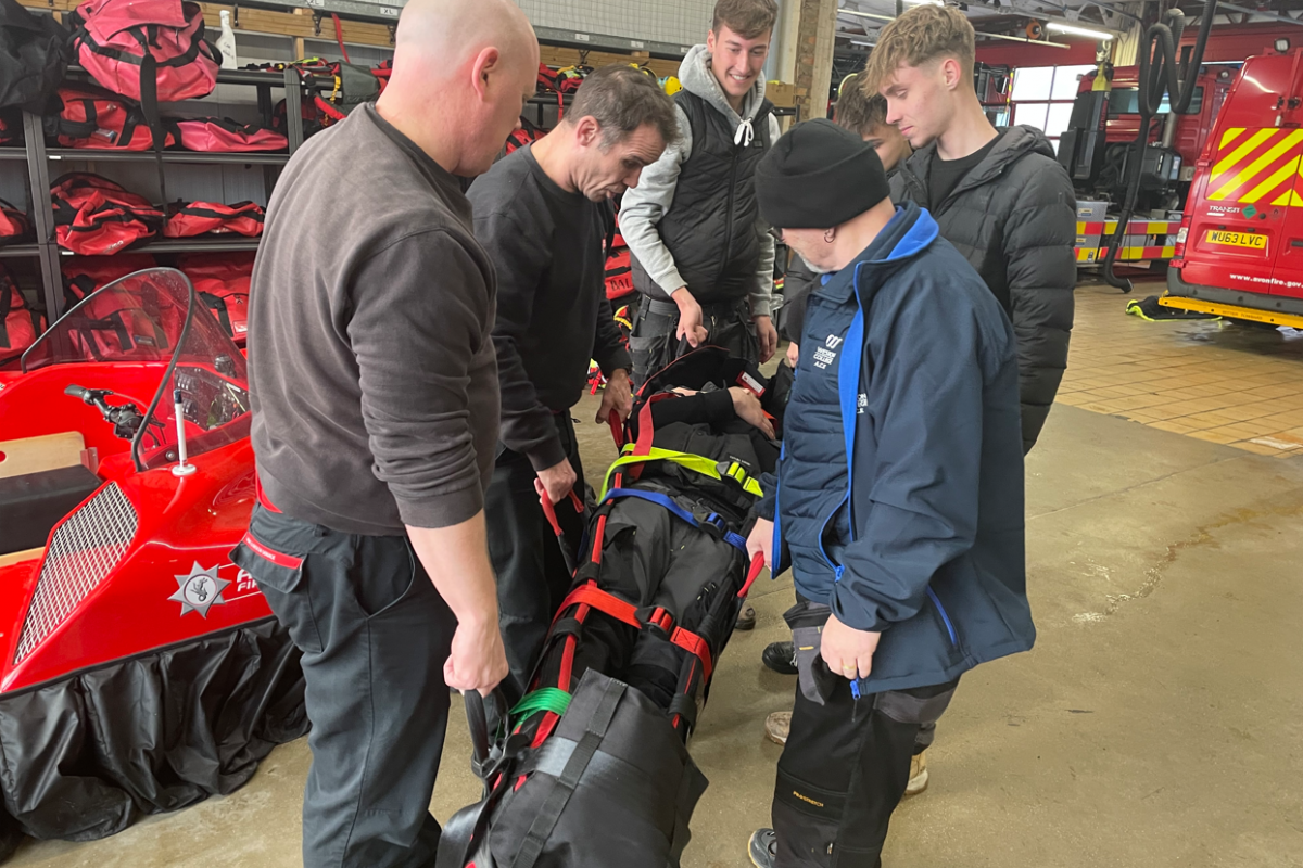 students picking up a stretcher with a student strapped in 