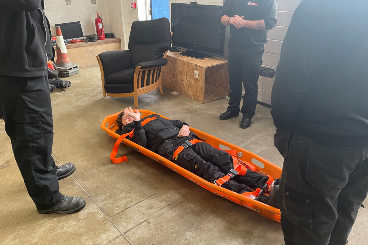 student strapped in a stretcher with his thumb up 