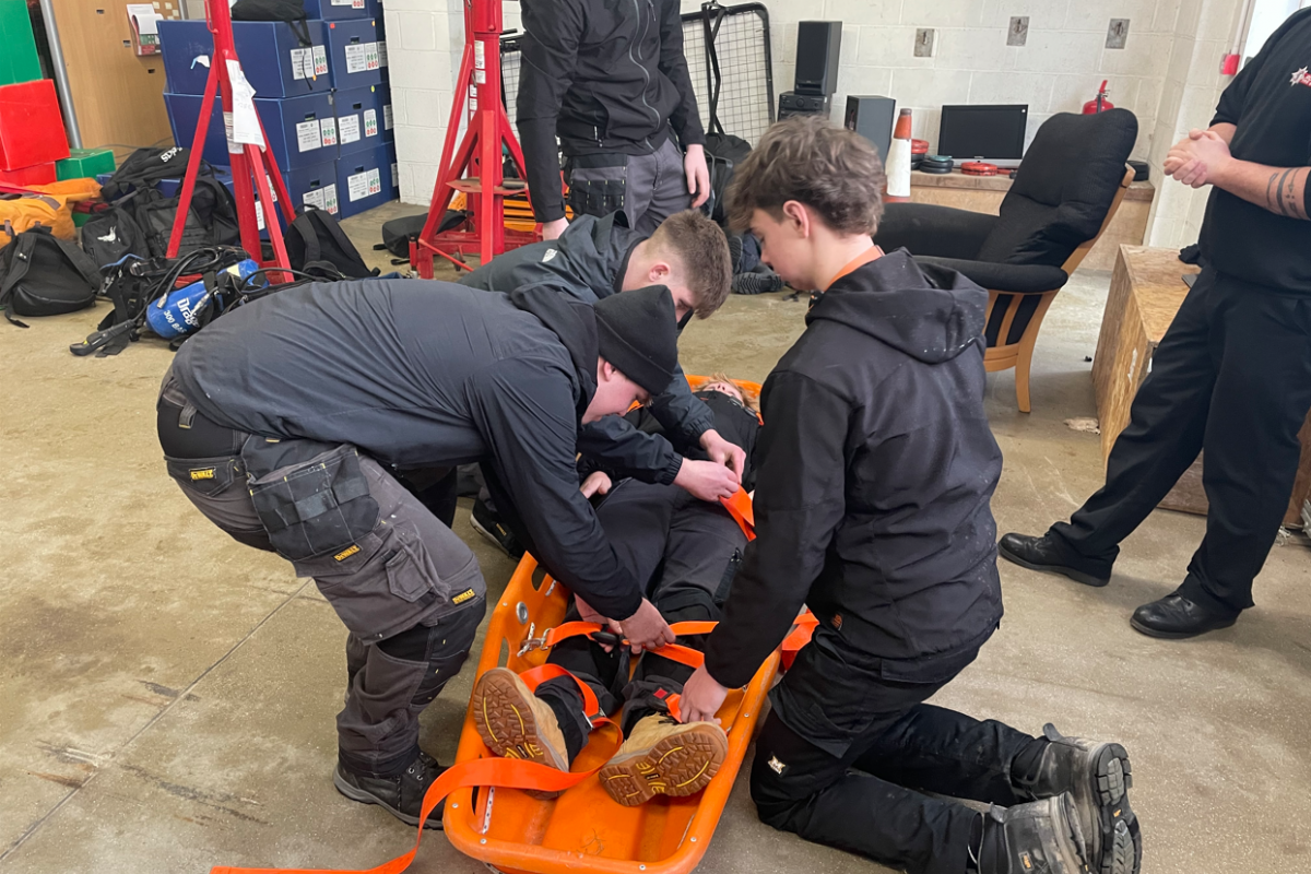 students strapping in another student onto a stretcher 
