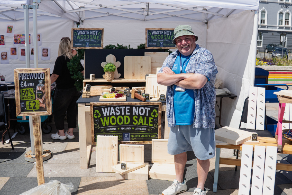 lecturer stood with carpentry pop up shop selling chopping boards and other wooden items 