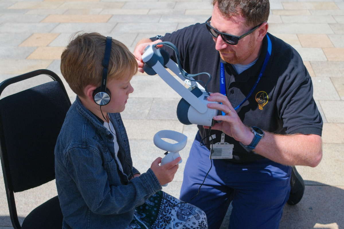 Attendees using VR headset with college staff
