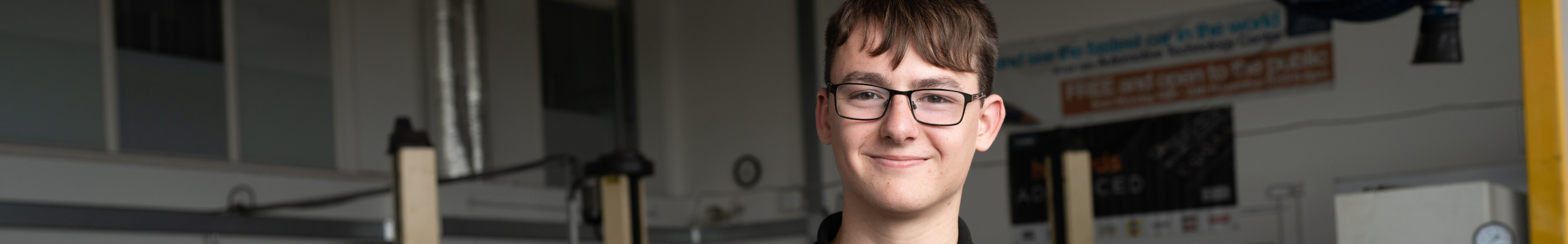 male motor vehicle student in front of car in workshop