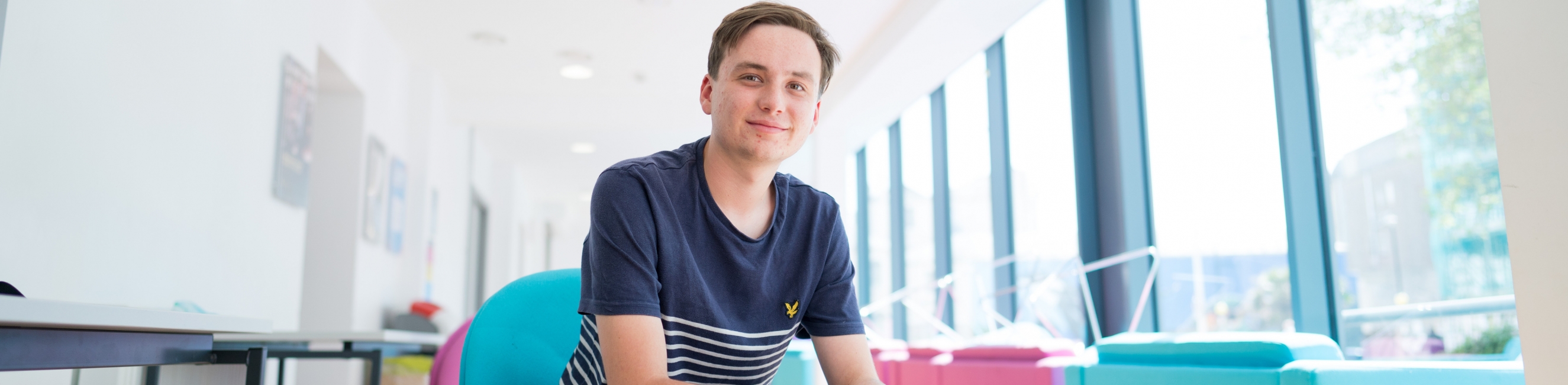 student sat on blue chair smiling at camera studying business course for 16 year olds leaving school from year 11 in weston super mare