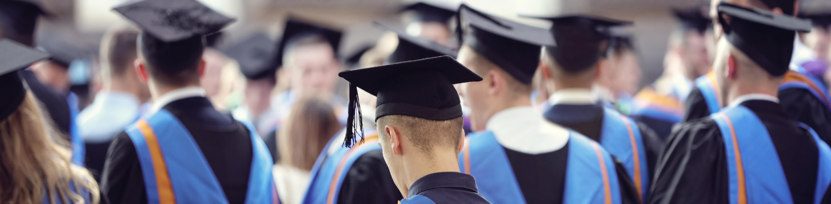 photo of the back of  a group of university learners in black, blue and orange graduation gowns 